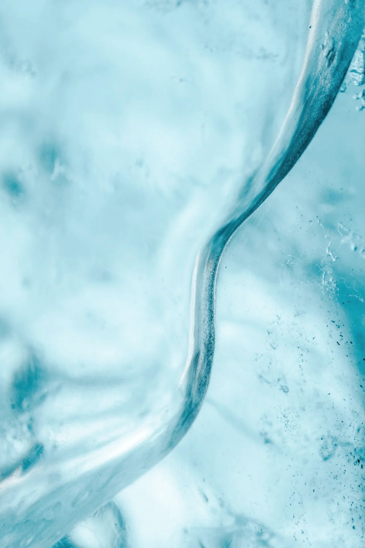 Close-up of a spoon submerged in clear ice with blue tint, showing cold and frozen textures.