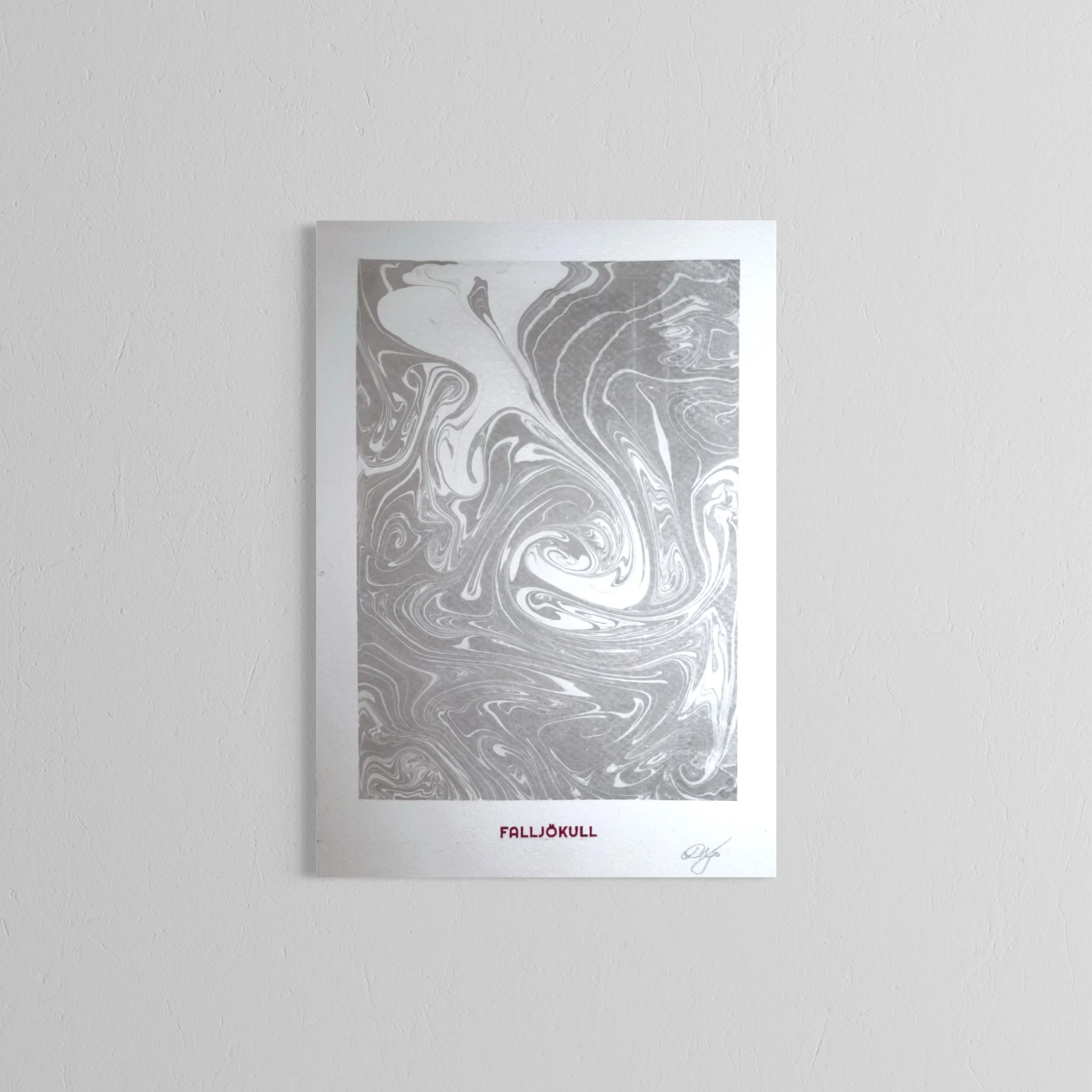 A handmade print with a marbled gray and white design titled "FALLJÖKULL" is taped to a plain white wall.