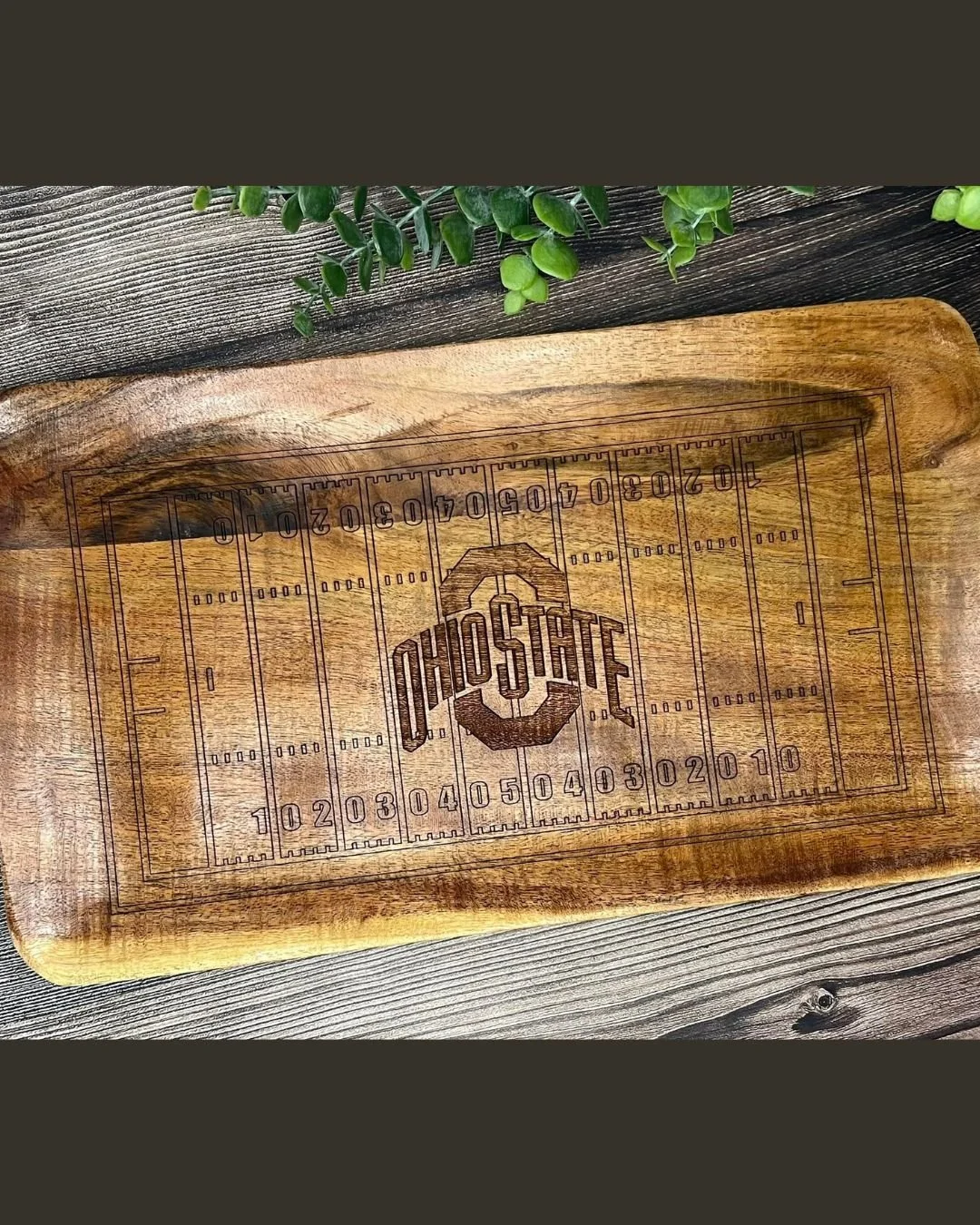 Custom engraved wooden Ohio State Buckeyes themed tray with yard line markings and Ohio State logo, topped with green plant.