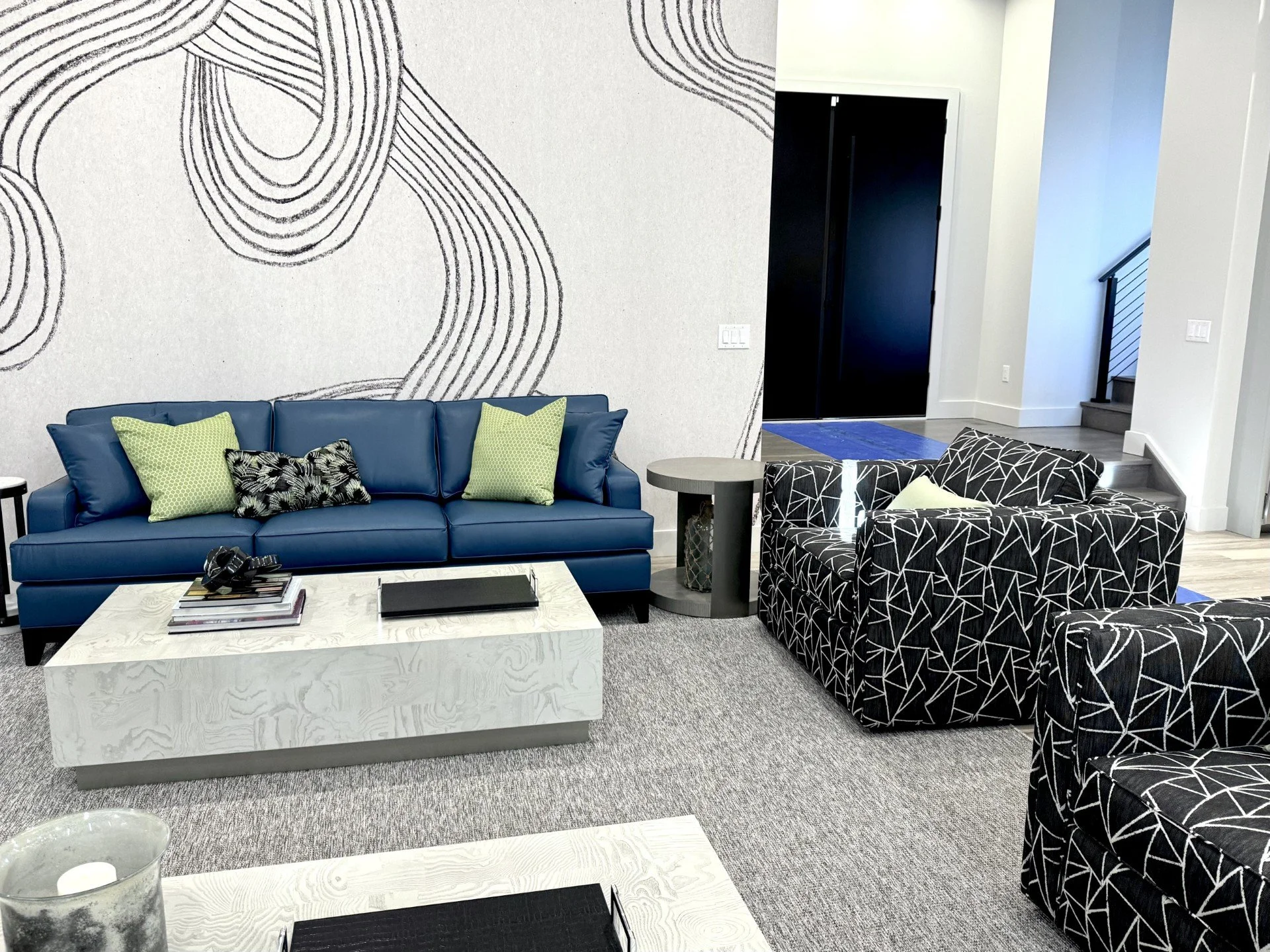 Modern living room seating with teal faux leather sofa, patterned pillows, marble drink table and graphic wallpaper