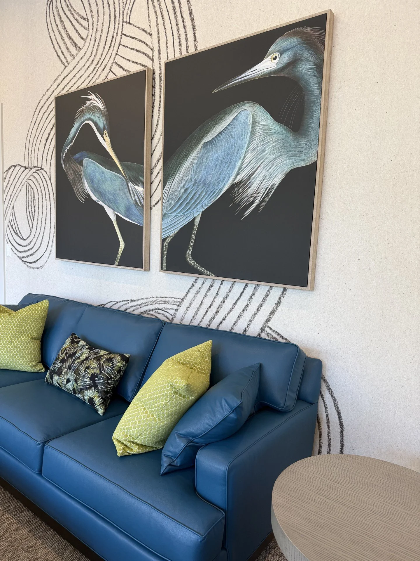 Colorful modern living room with teal sofas, black print swivel chairs, and graphic wallpaper in a Rehoboth Beach home