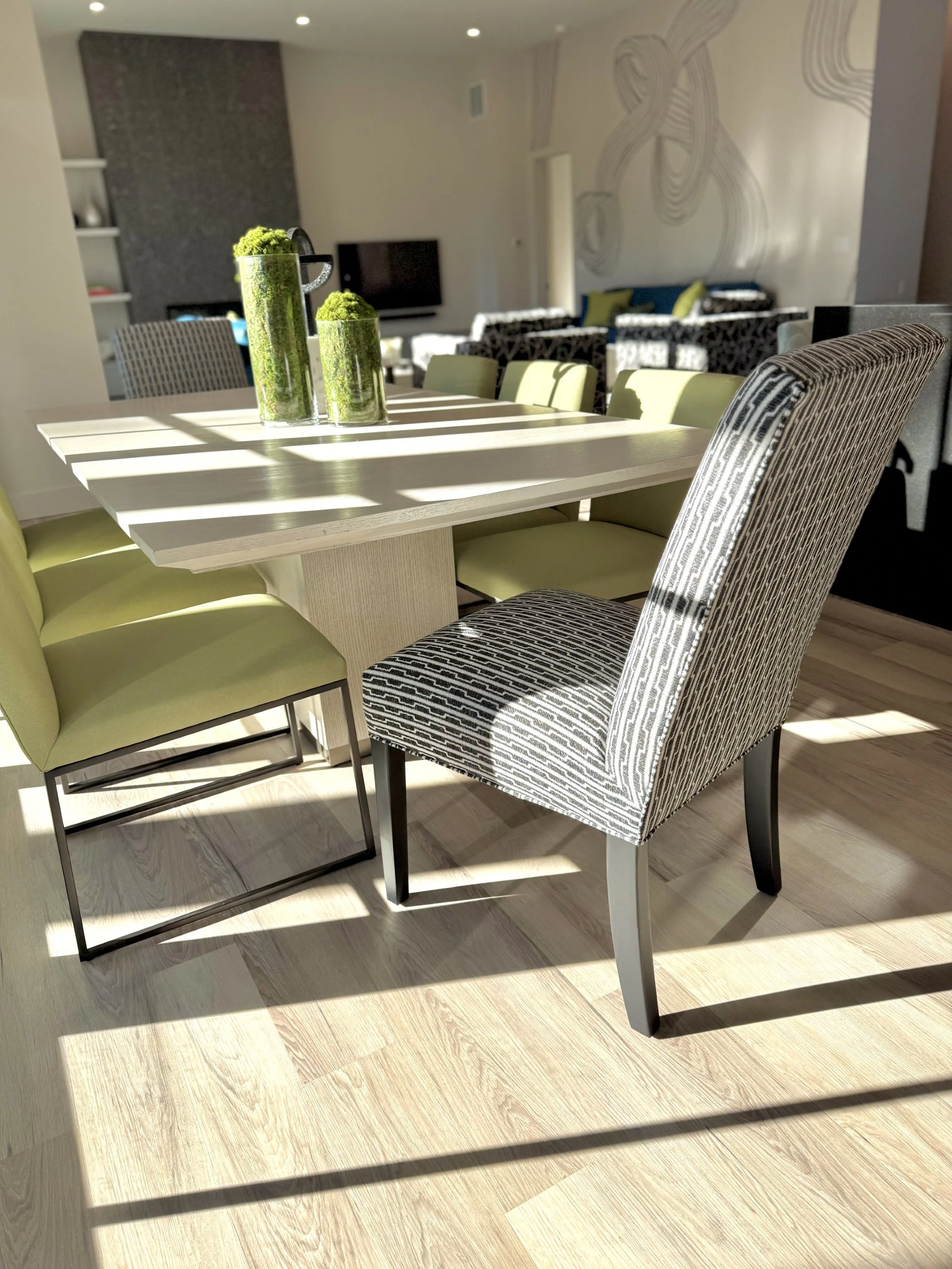 Colorful modern dining area with green dining chairs and black patterned head chairs