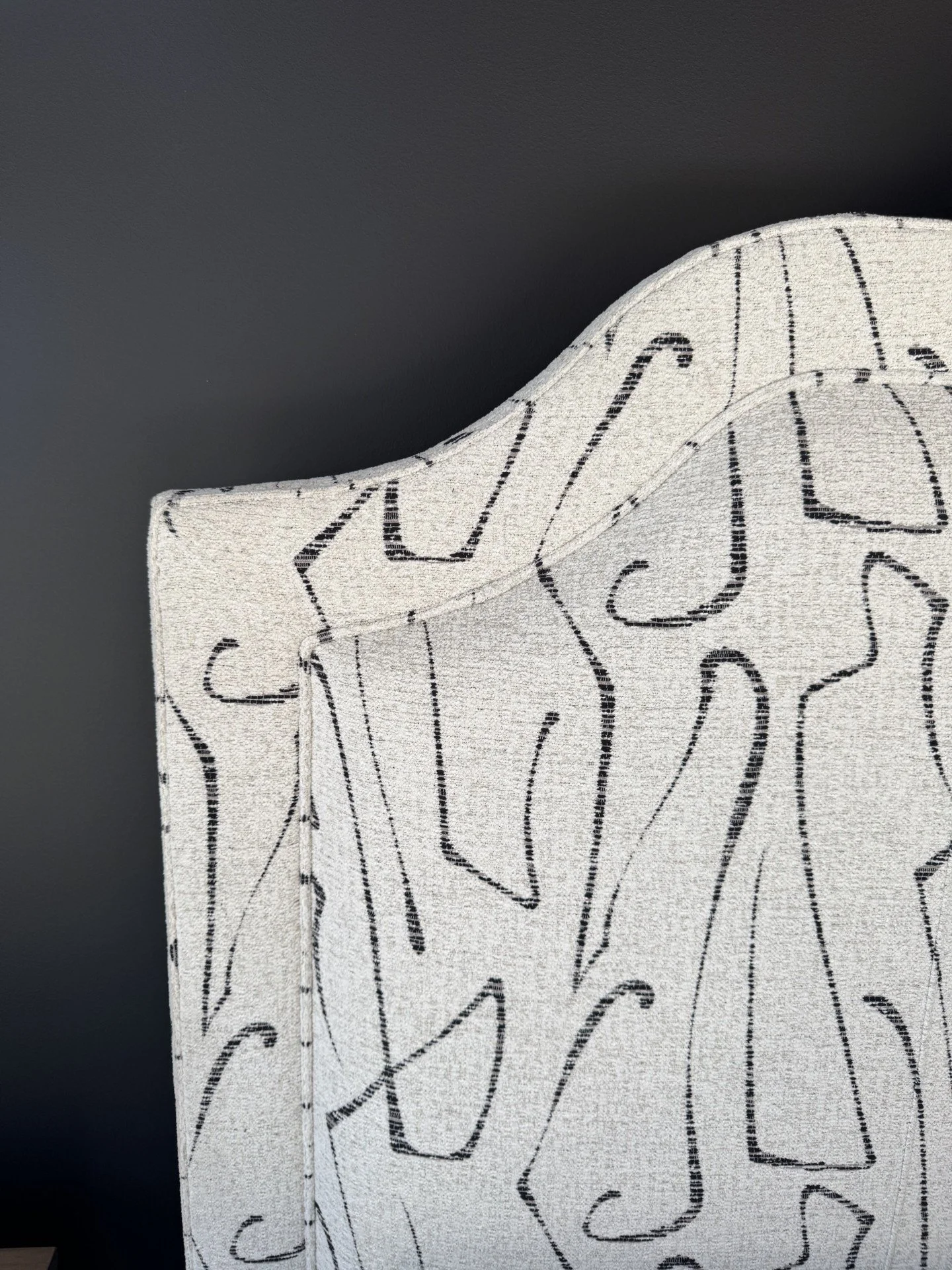 Modern patterned headboard against black bedroom wall and ceiling