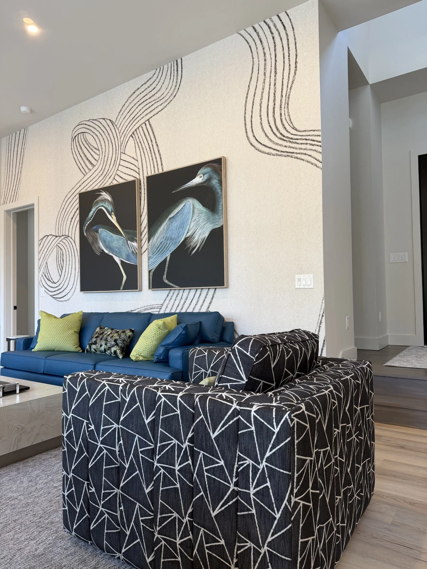 Colorful modern living room with teal sofas, black print swivel chairs, and graphic wallpaper in a Rehoboth Beach home