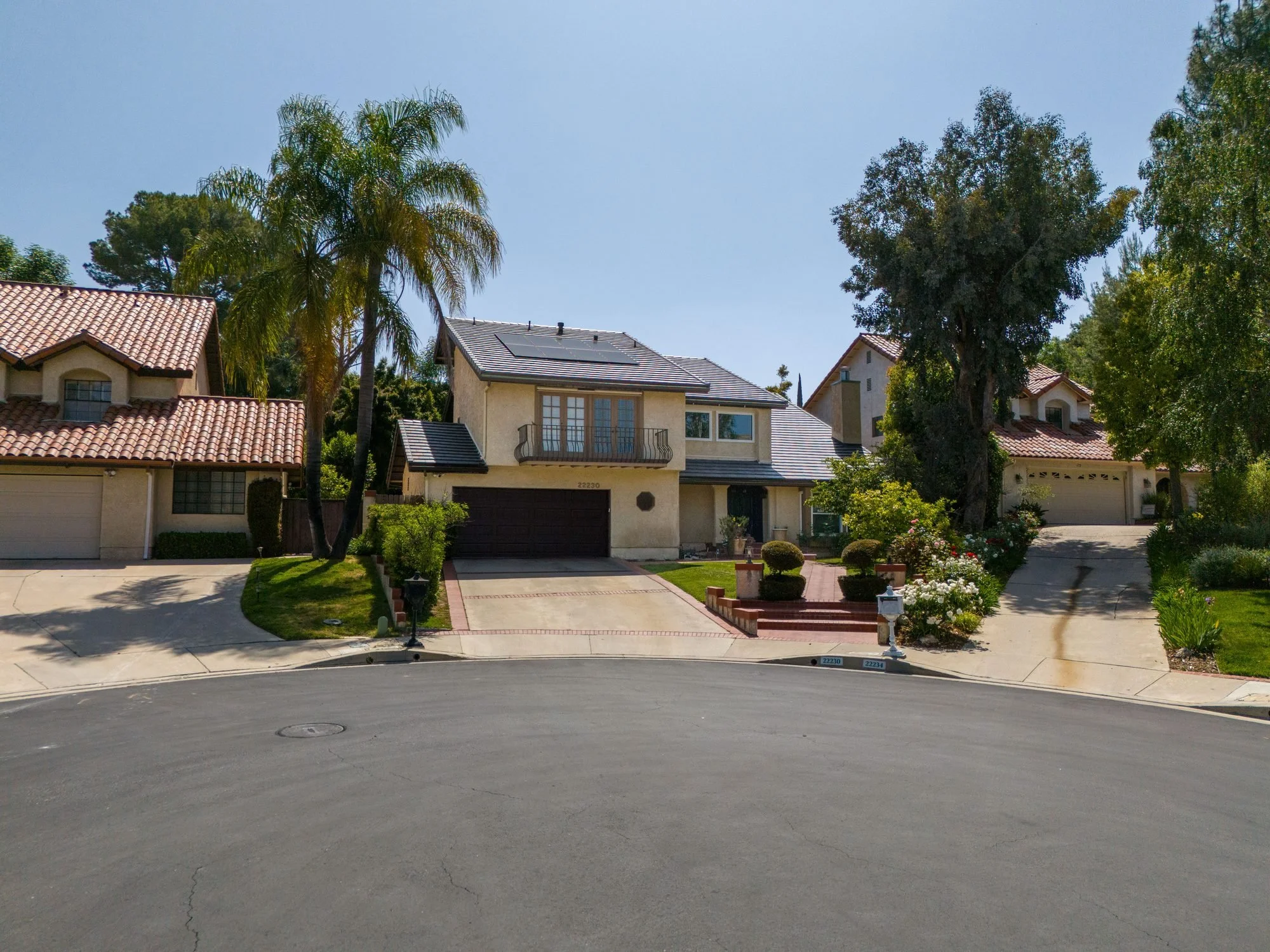 Low-angle drone real estate photo of a Calabasas cul-de-sac home with palm trees