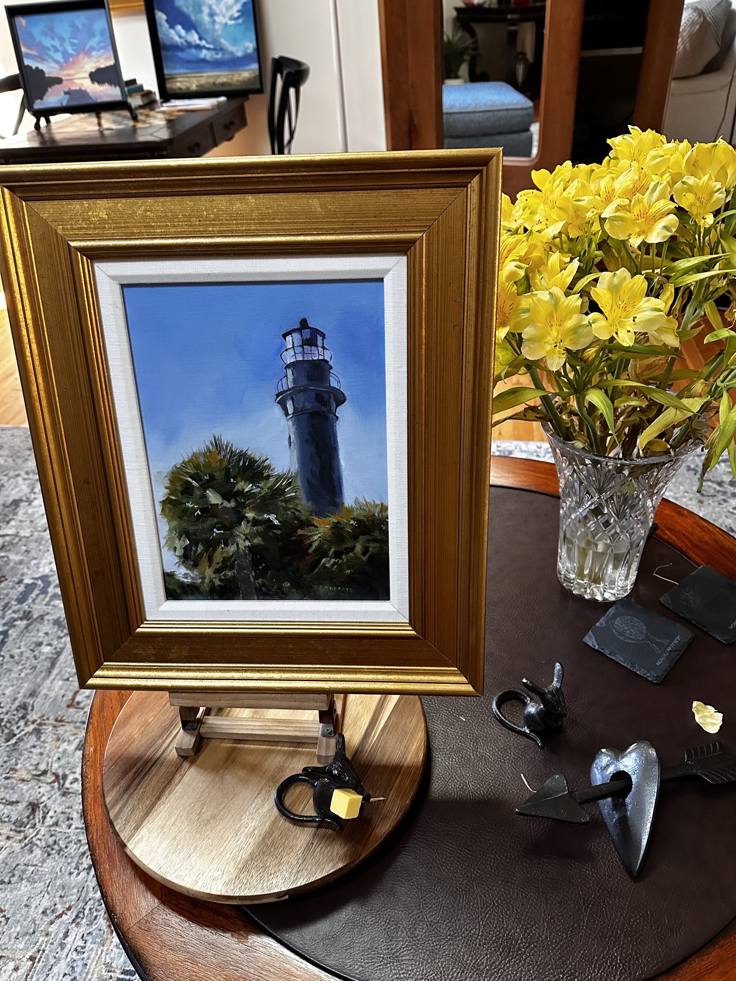 Oil painting of a historic lighthouse on the South Carolina coast, surrounded by palm trees.