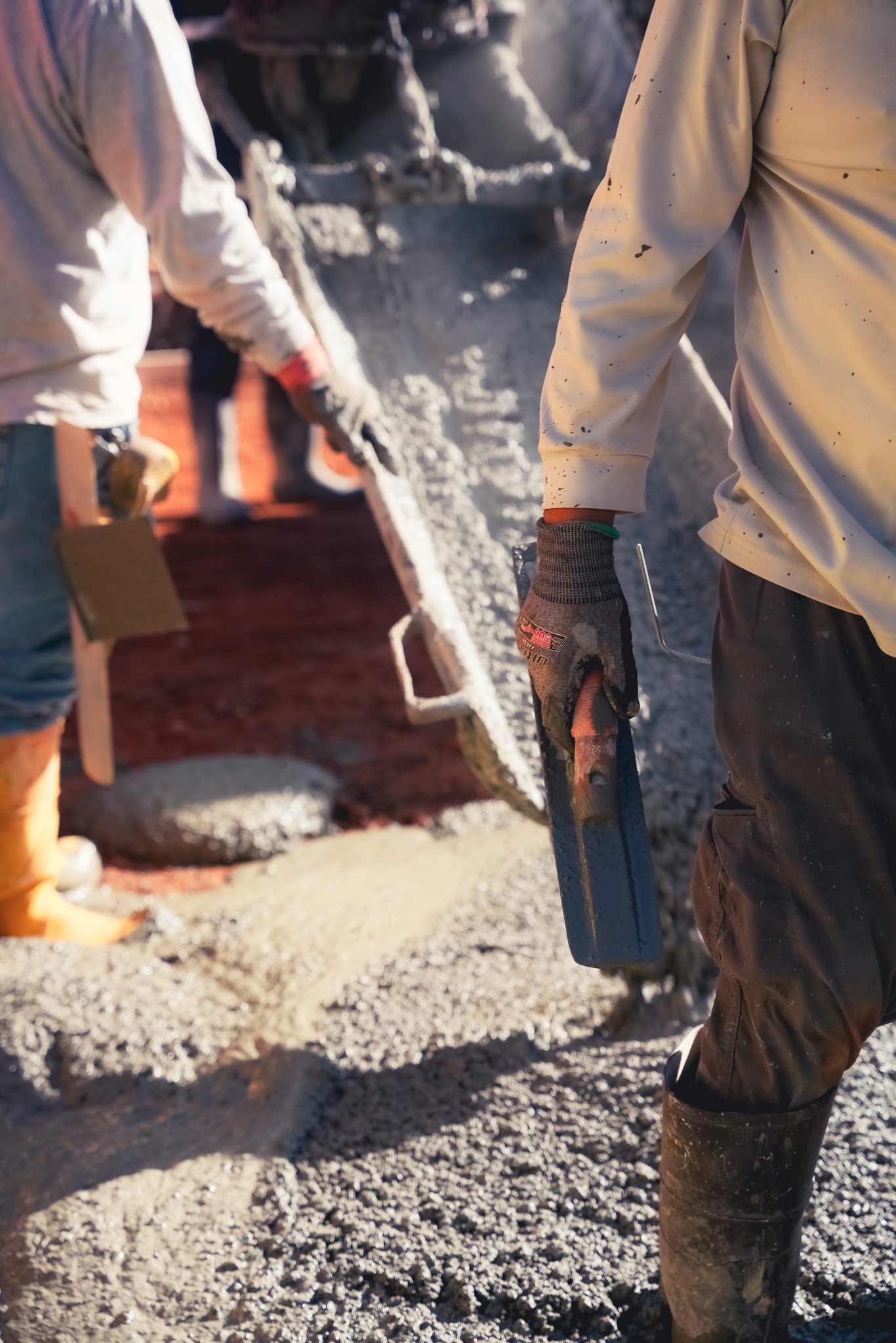 Close-up of construction workers pouring concrete into a form.