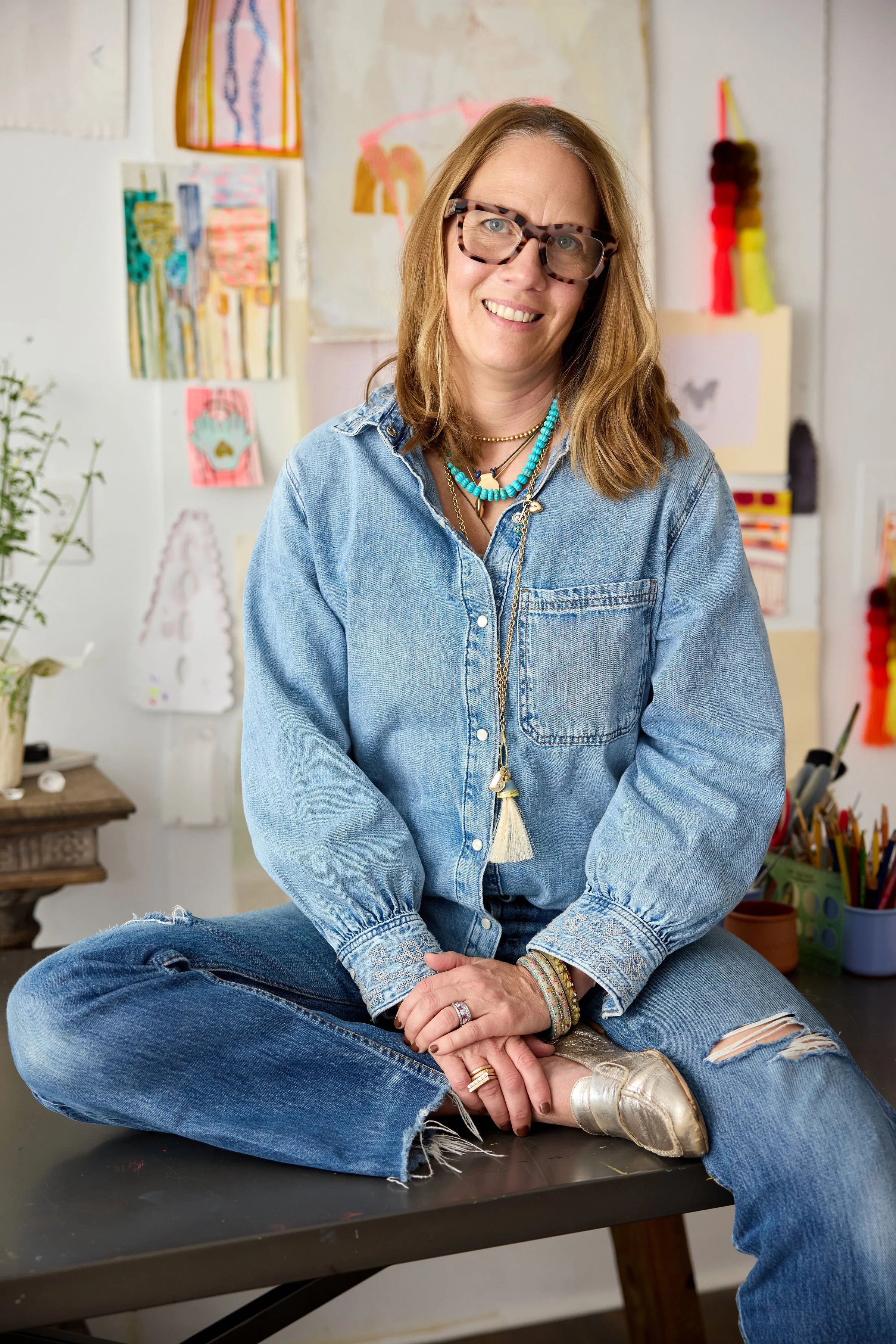 Elaine Chong sitting on table smiling at camera in studio