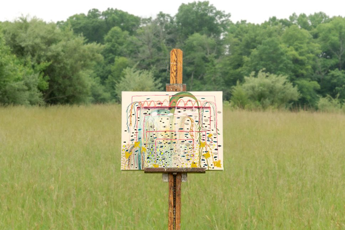 Painting on easel in field of green grass