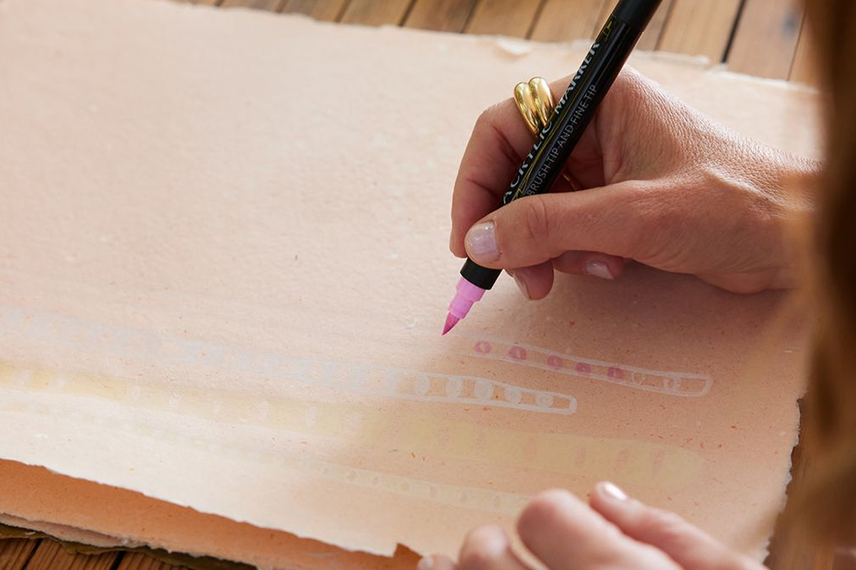 Detail of Elaine sketching out design with pink marker in hand