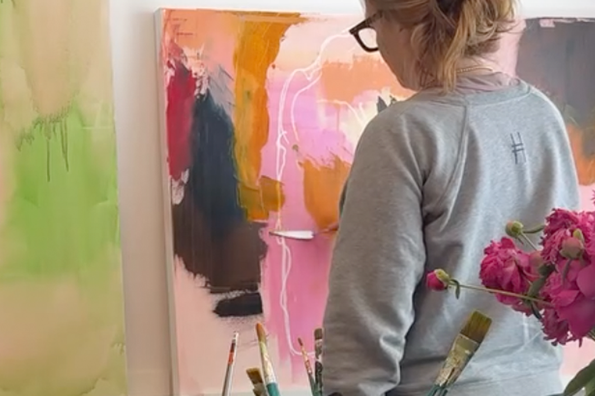 Elaine Chong standing and painting on canvas