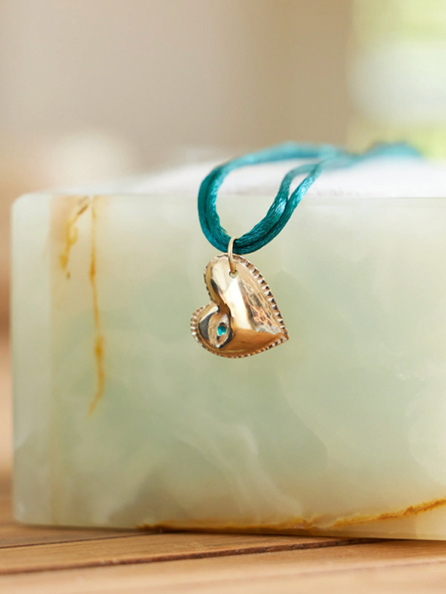 Puffy heart pendant on turquoise cord styled on block
