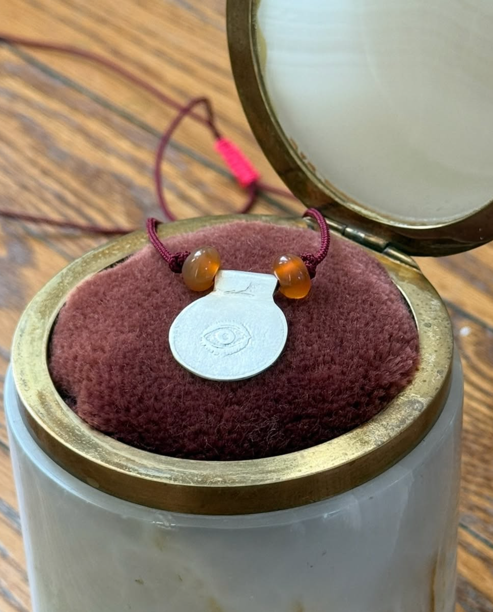 Elaine Chong's Sterling Silver Coin Pendant on cord styled on red cushion