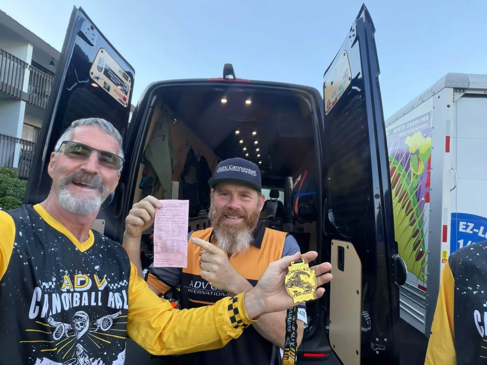 A pink trespass warning slip and a finisher's medal held up for the camera at the back of a van