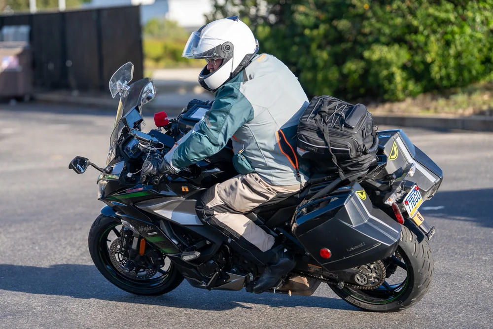 A rider leaning a Kawasaki Ninja 1000SX with luggage through a turn