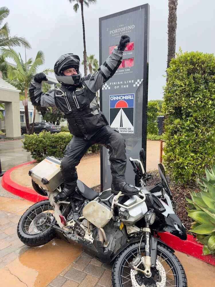 Competitor standing on the seat of a motorcycle with a fist in the air