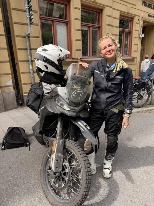 Eglė Gerulaitytė standing next to her motorcycle in a studio in Sweden