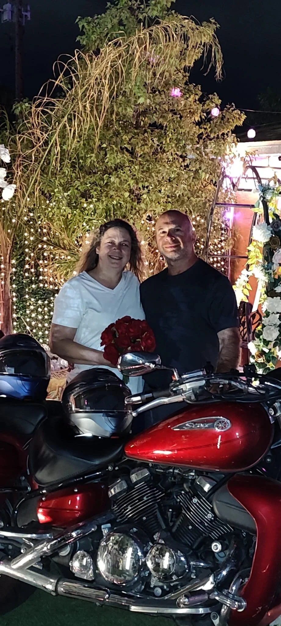 Chris and Kathleen standing behind their Yamaha Royal Star at a chapel at night