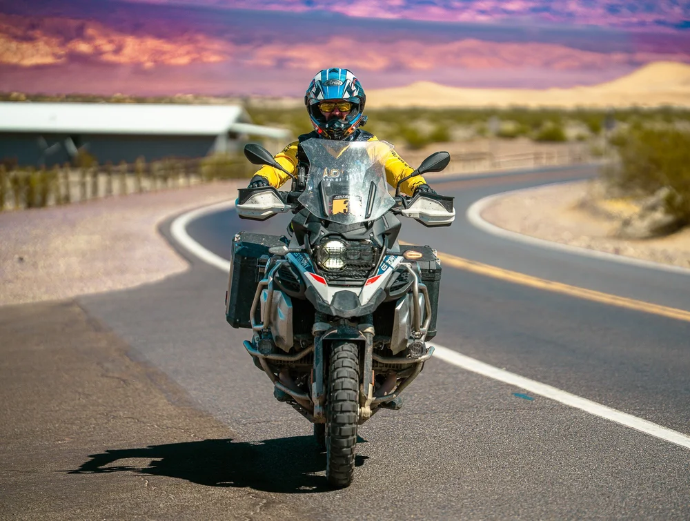 Sean Ross riding his BMW toward the camera on a desert road