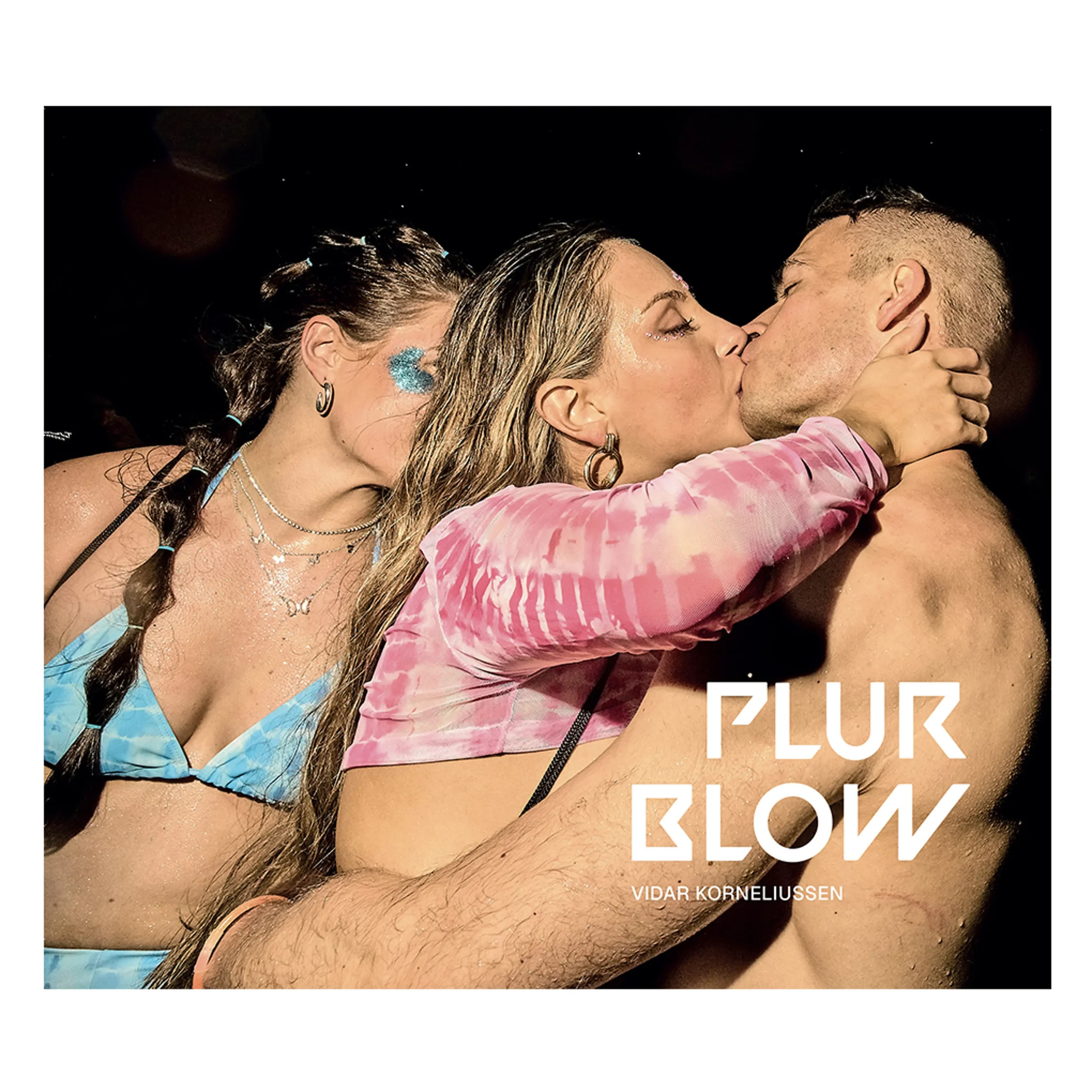 Three people, two women and one man, are engaged in a close, intimate moment, sharing a kiss. The woman in the foreground wears a pink, tie-dye, long-sleeve top, and has her arms around the man's neck. The woman behind her is dressed in a blue bikini top with a braid in her hair, and the man has short hair and is shirtless. The image has a dark, out-of-focus background with some light spots, and the text 'PLUR BLOW' and 'VIDAR KORNELIUSSEN' is overlaid.