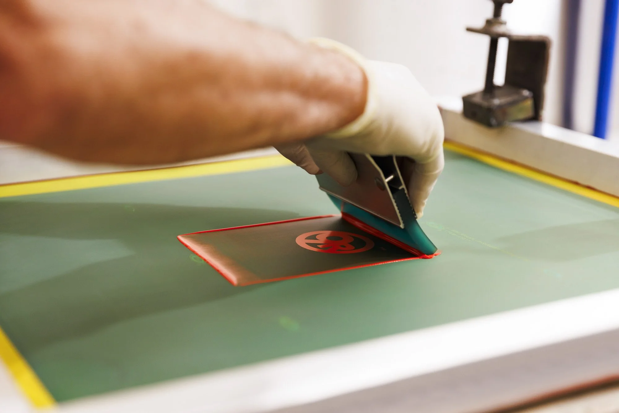 screen printing squeegee applying ink across stencil showing controlled ink coverage and print application process