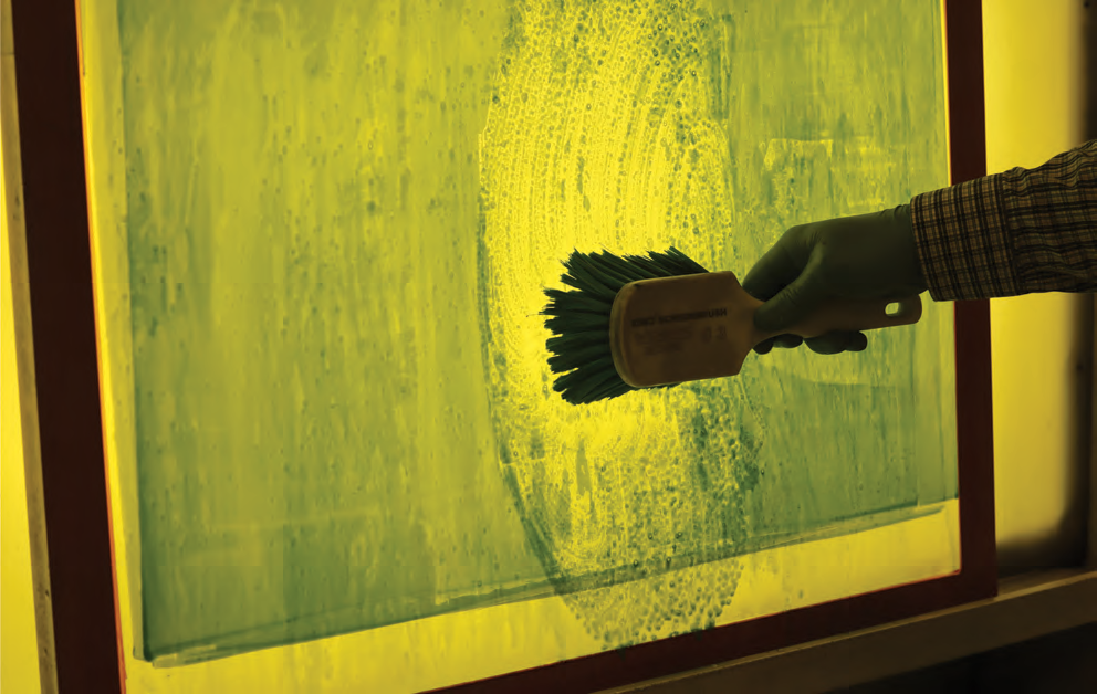 screen printing screen cleaning with brush and chemicals showing safe handling and controlled application in screen room process