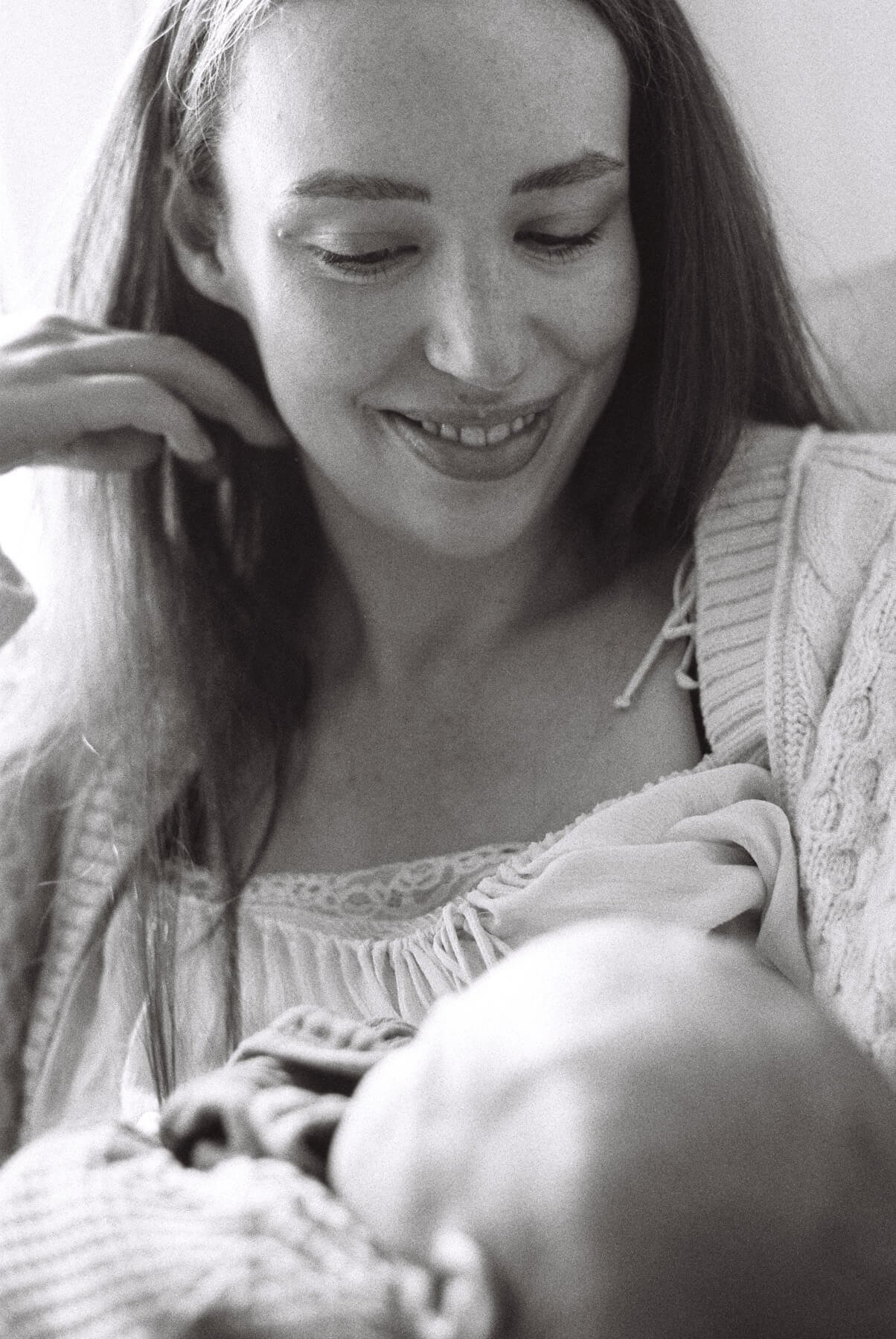 Newborn photography in Berlin: mother looks at her newborn daughter and smiles