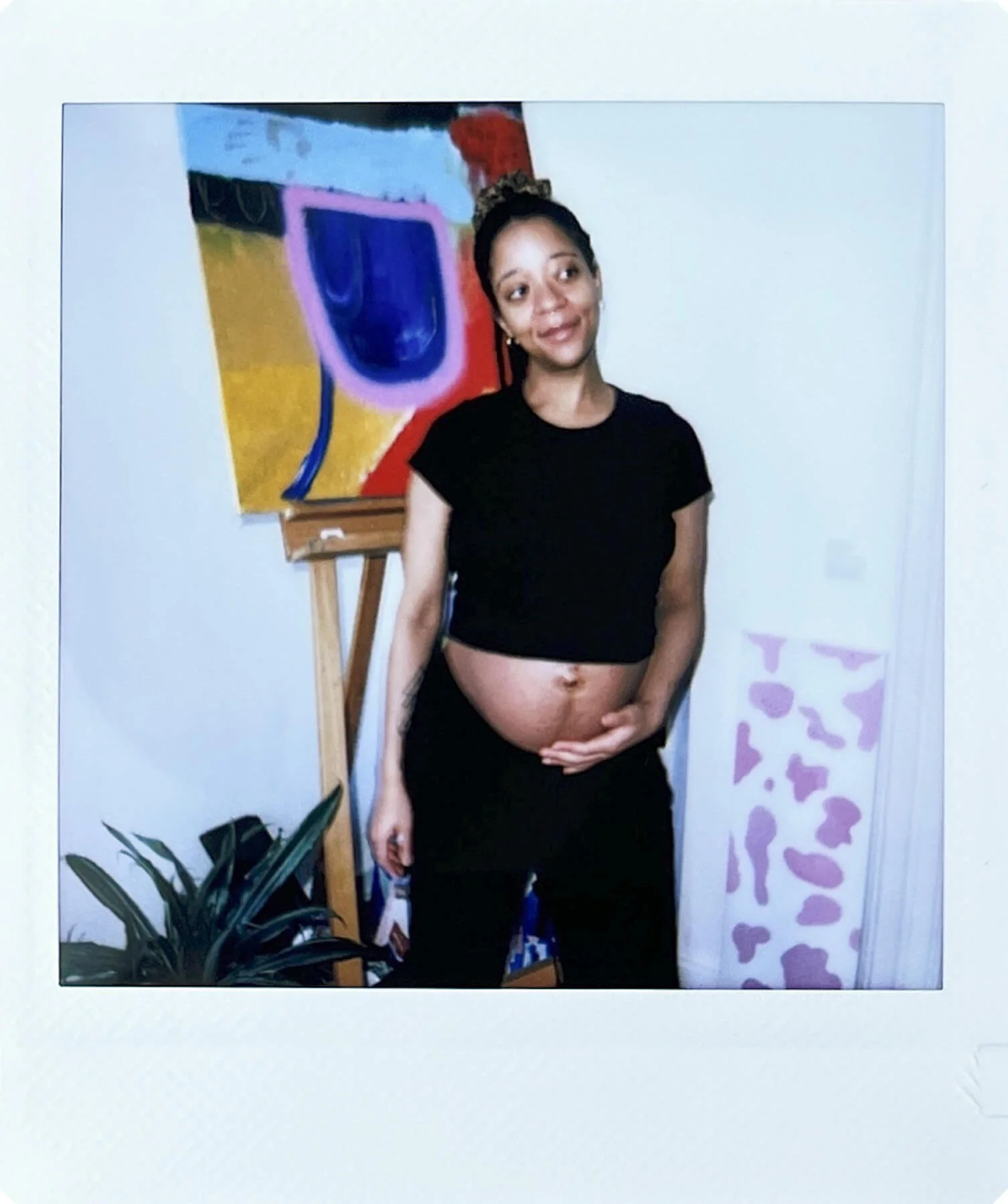 Polaroid einer schwangeren Frau vor einem bunten Gemälde – festgehaltene Erinnerung aus der Babybauchfotografie in Potsdam
