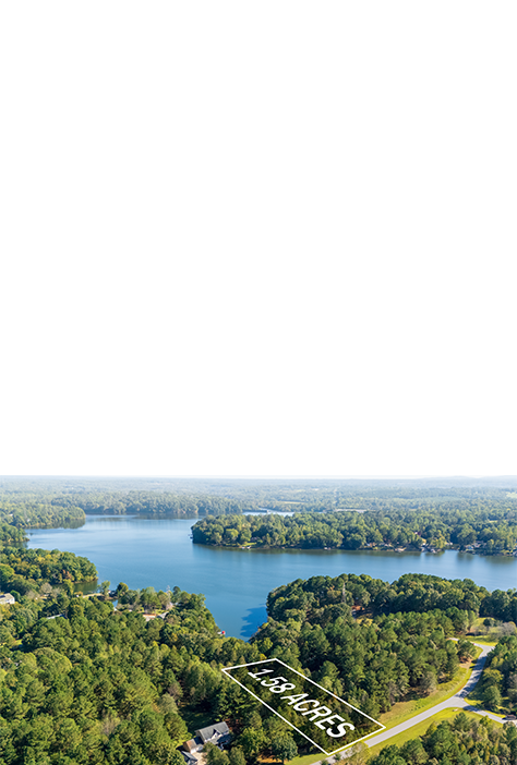 Aerial view of a large lake surrounded by dense green forest and a few residential properties, with a marked plot of 1.58 acres labeled on the ground.
