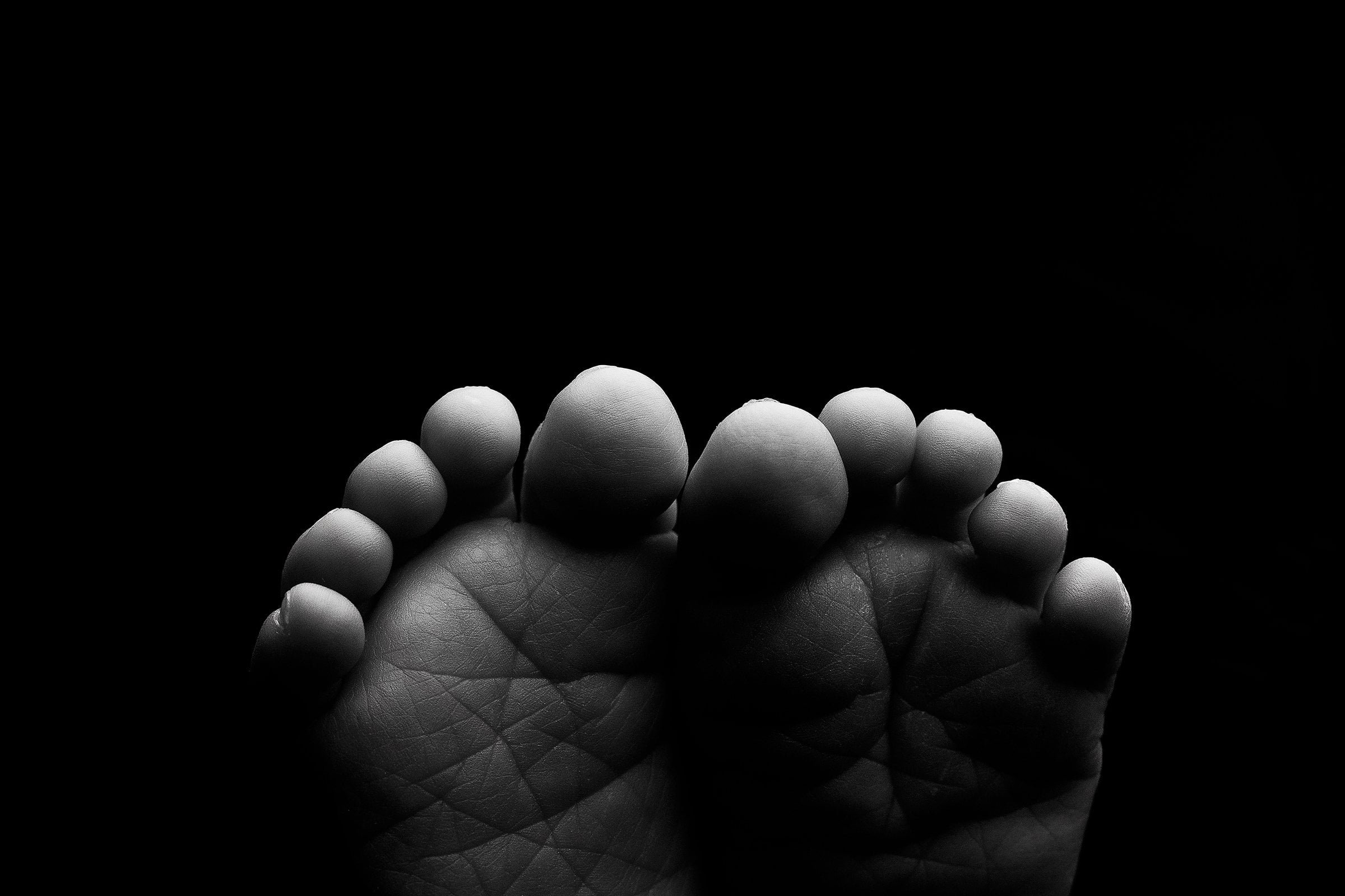 Black and white photo of a hand holding a group of small, round objects, possibly eggs, against a dark background.