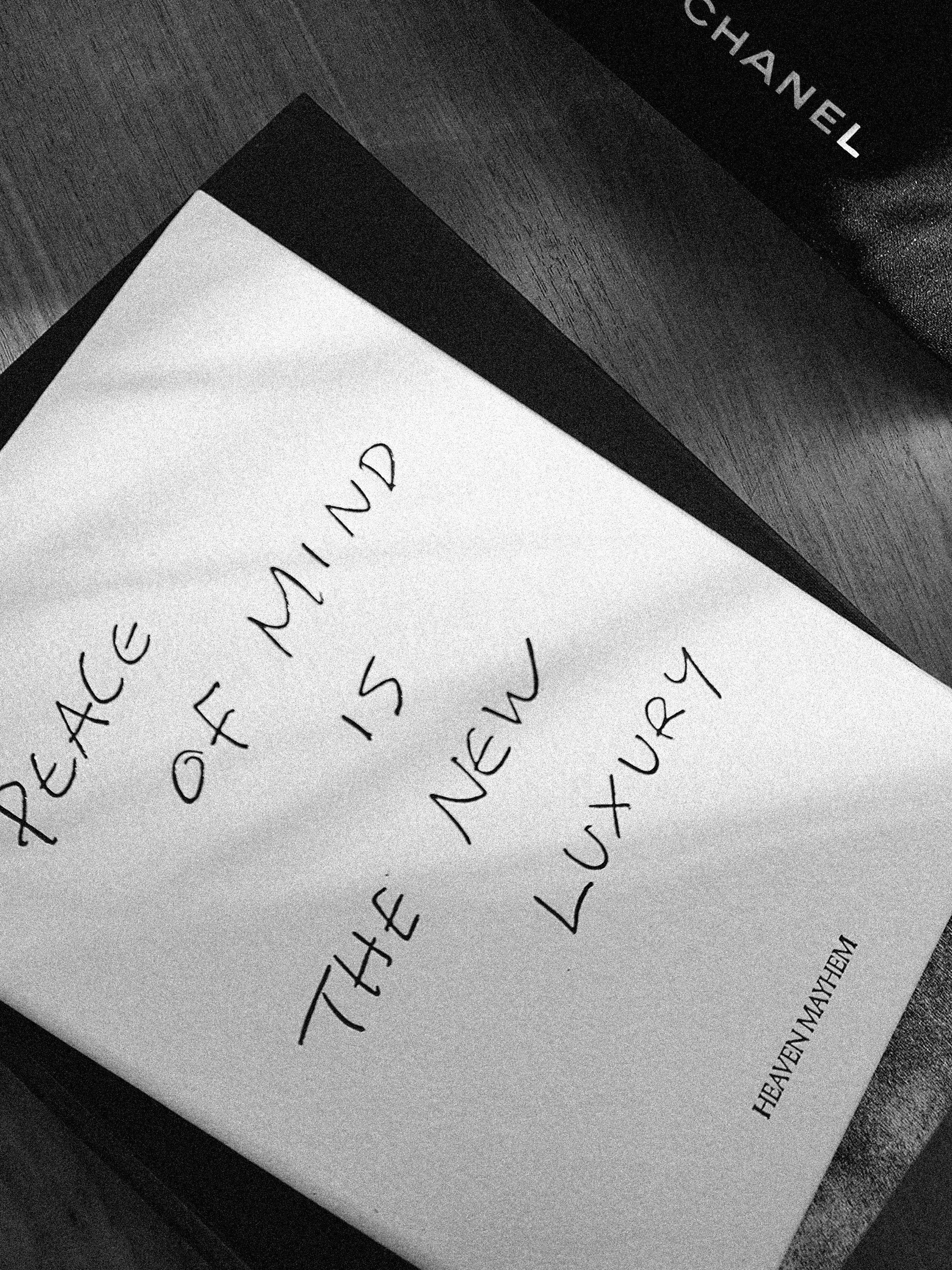 A handwritten note on white paper says "peace of mind is the new luxury".