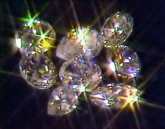 A close-up of several shiny, round diamonds reflecting light and creating sparkling effects against a dark background.