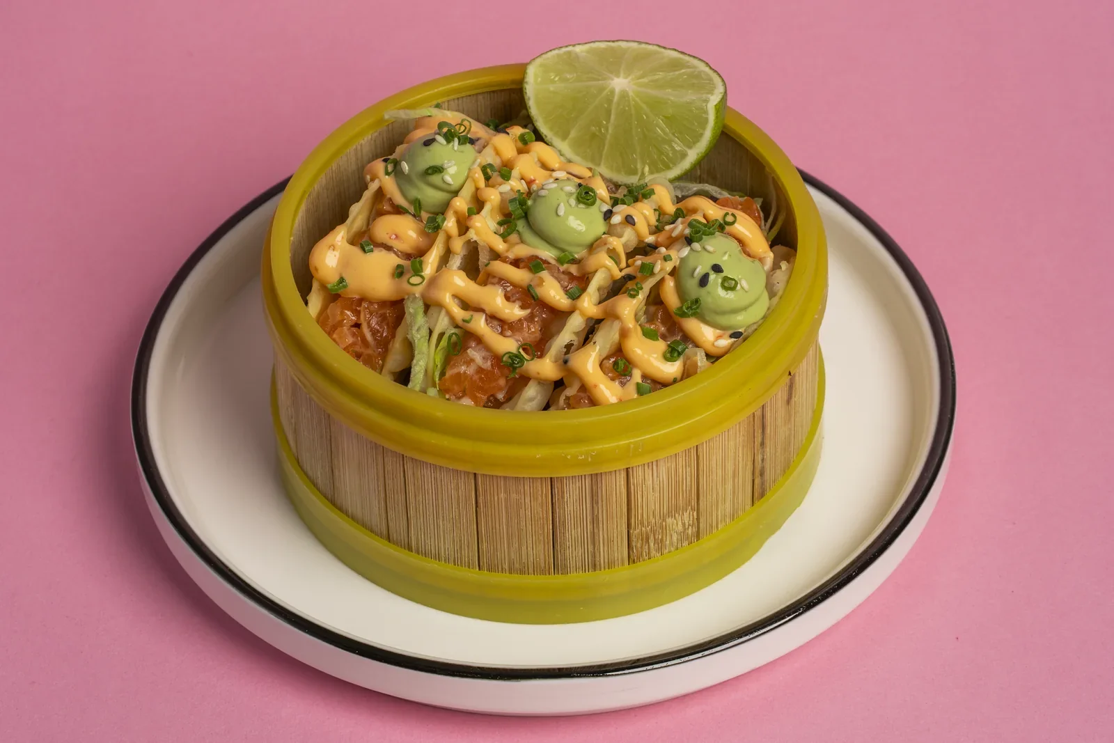 Noodles topped with vegetables and lime in a yellow bamboo basket.