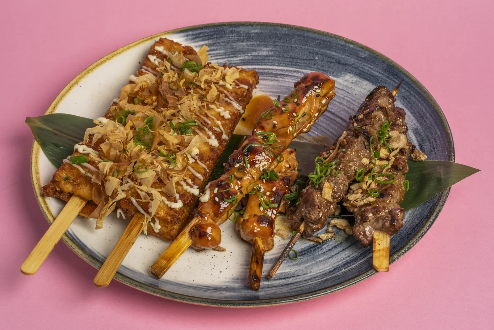 Glazed skewers served together on a dark platter.