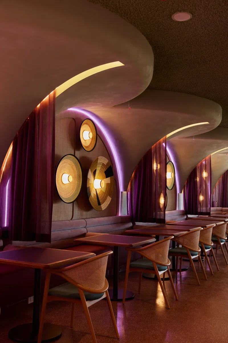 Dining tables alongside Jinja’s illuminated arch wall.
