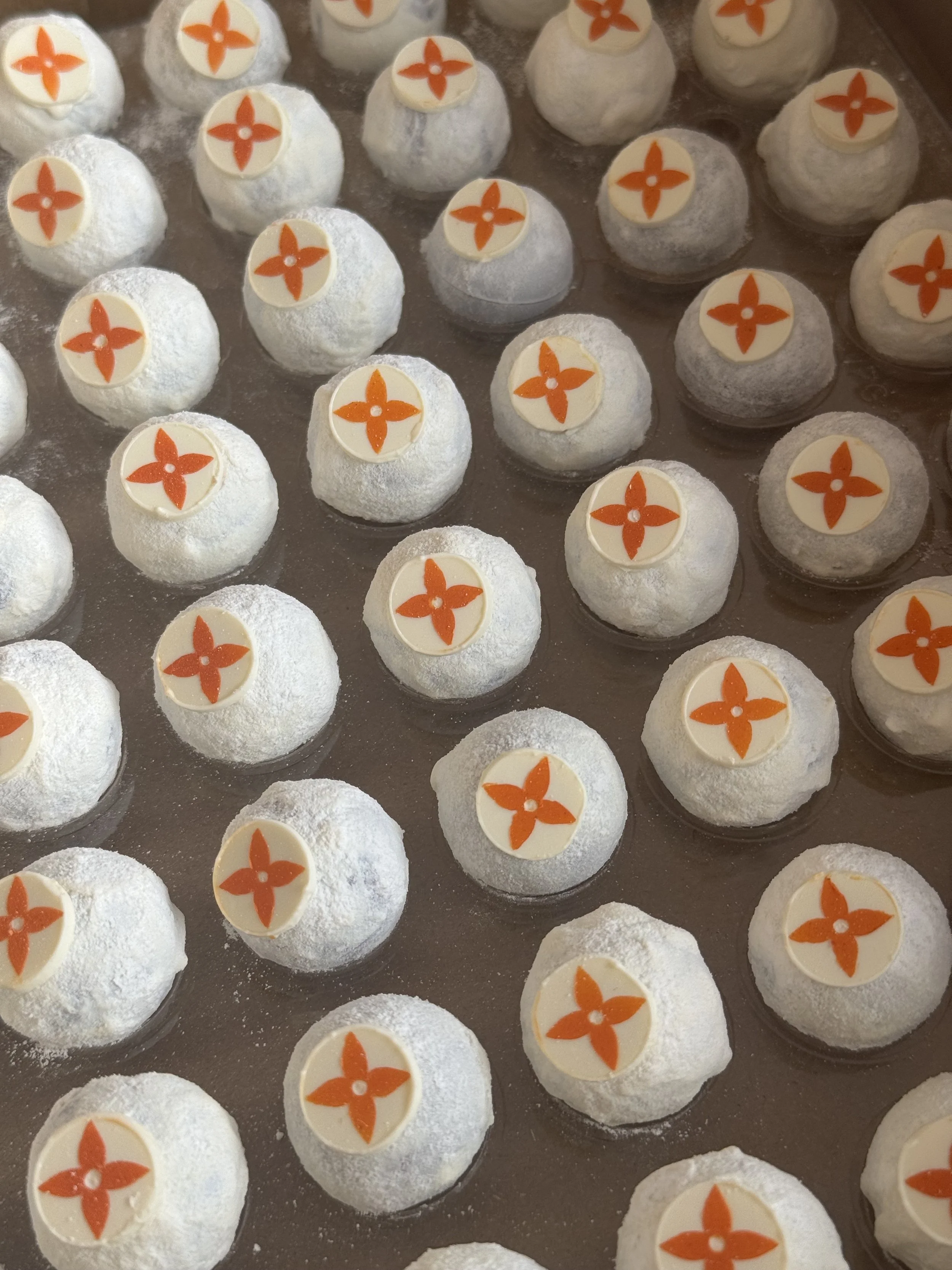 white chocolate truffles with orange and white decorative toppers, arranged on a baking sheet.