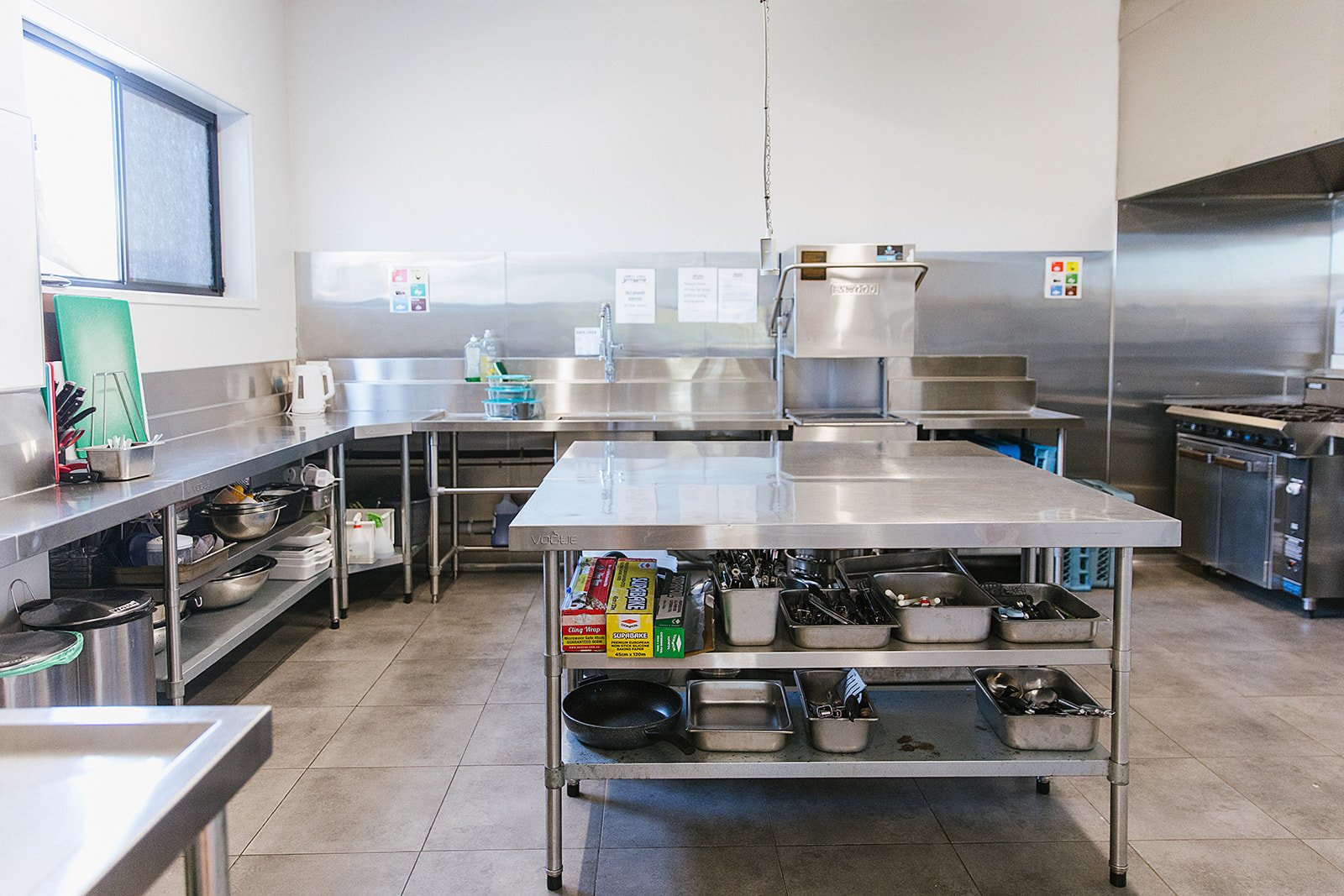 Commercial kitchen with stainless steel counters, shelves, and appliances. 