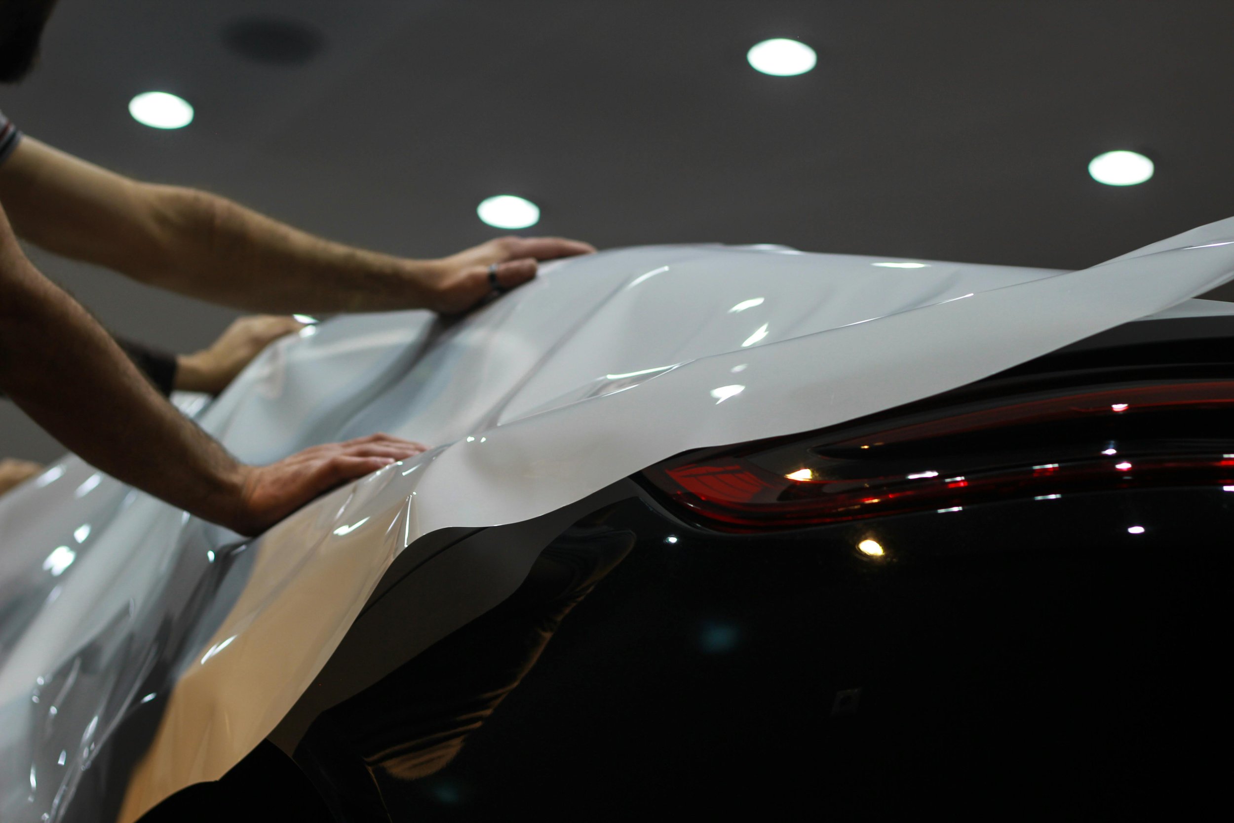People unveiling a white car at an auto show