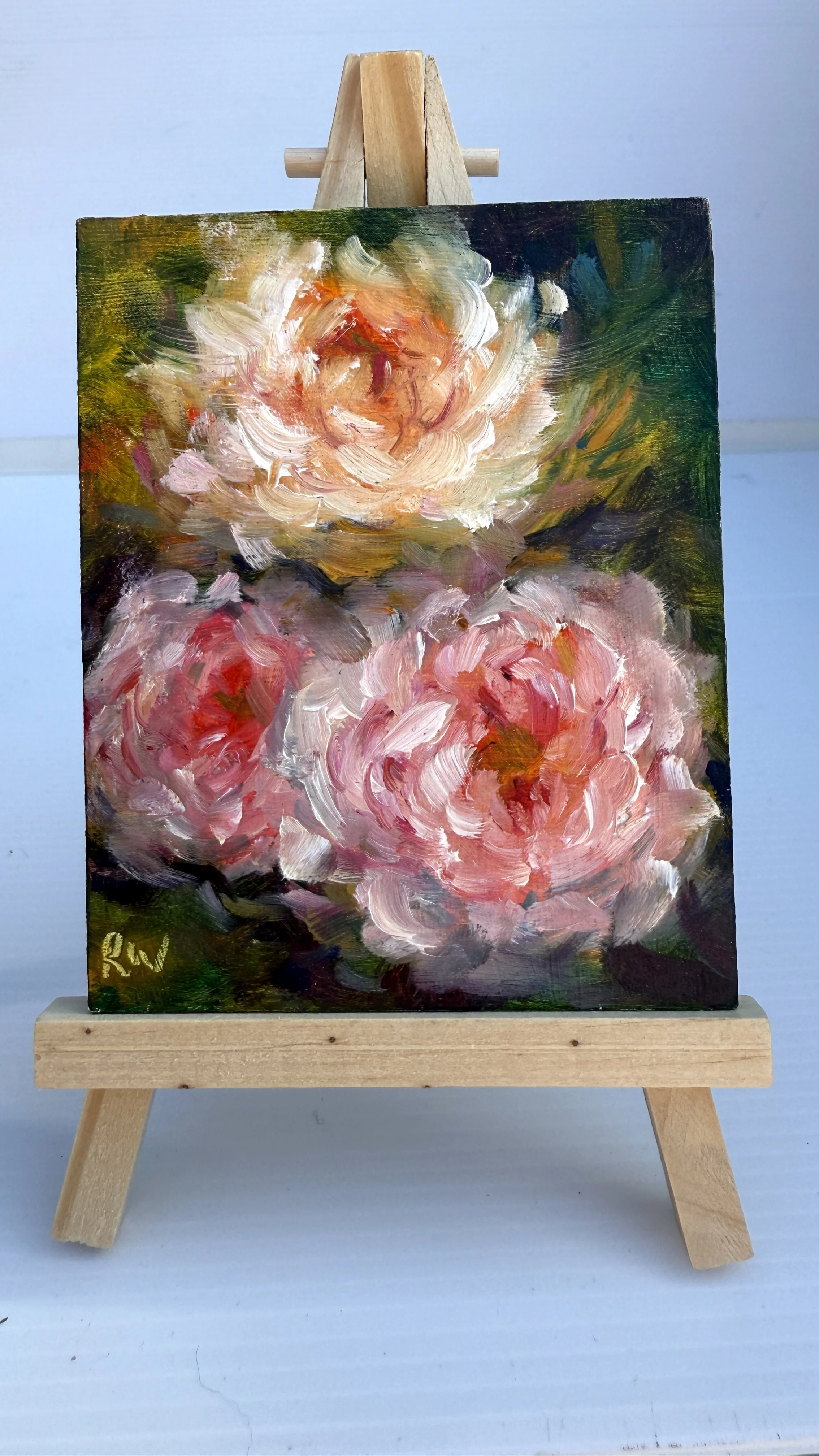 Mini oil painting of three soft pink roses, displayed on a wooden easel.