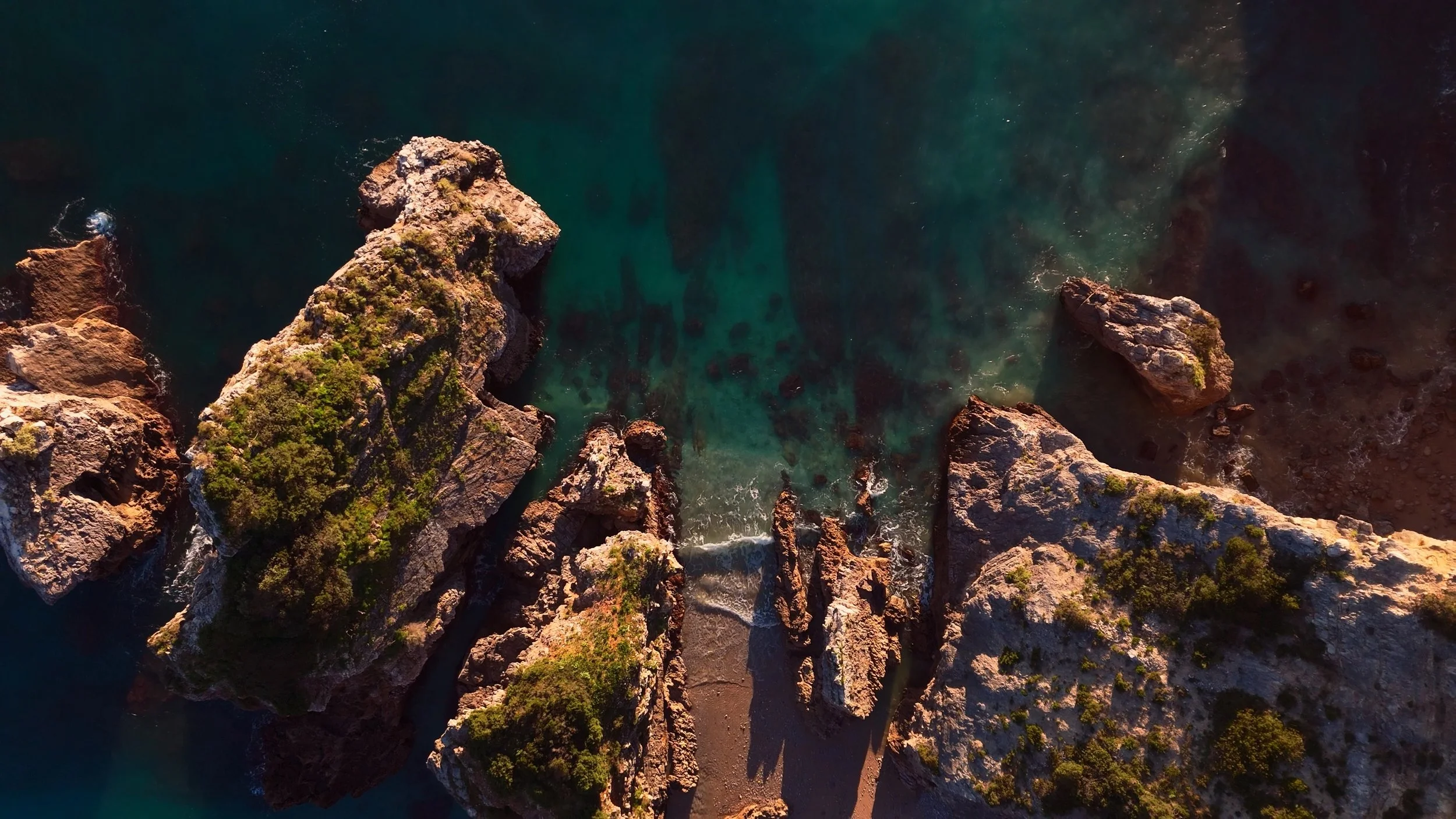 Top-down drone shot of coastal rocks and a turquoise tide pool, Portugal