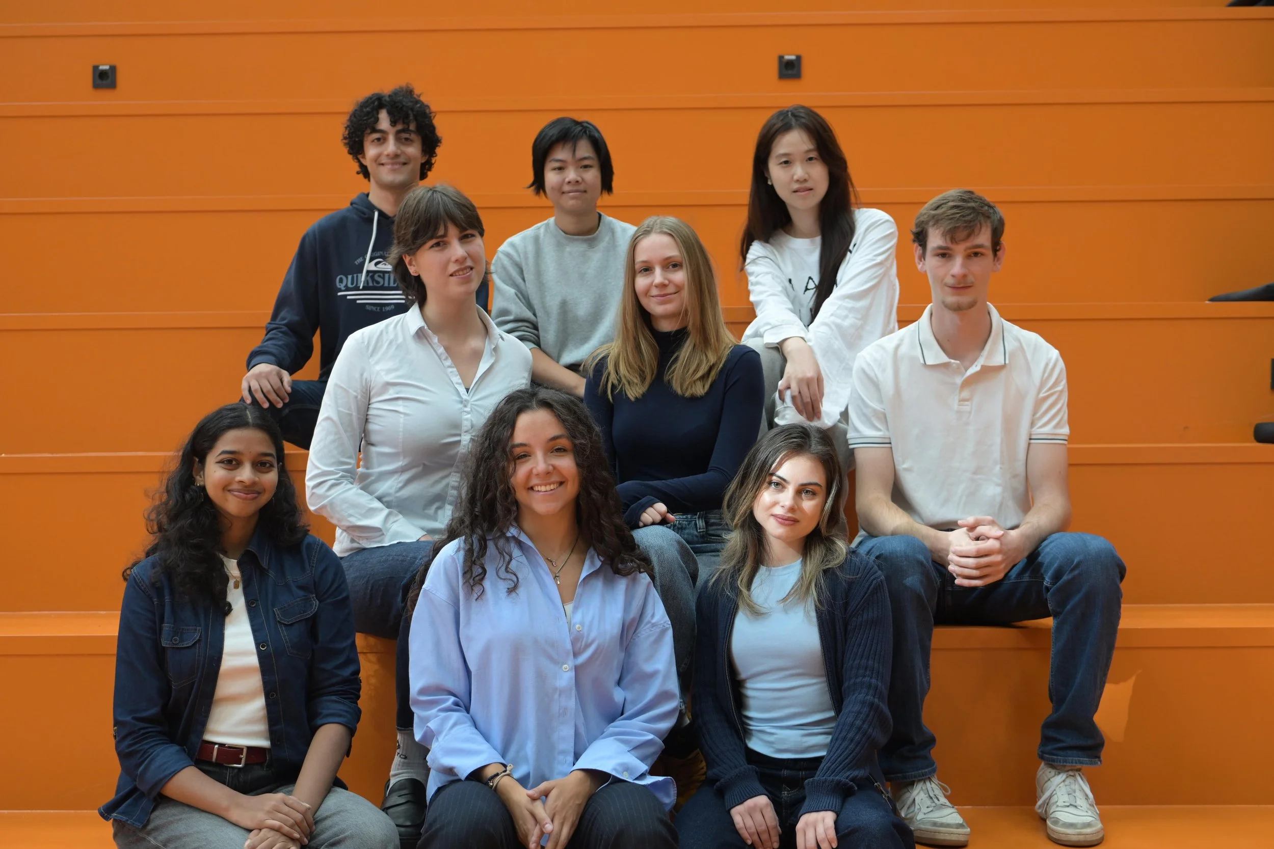 FLOW Team 26/27 on the orange steps at TU Delft Bouwkunde.