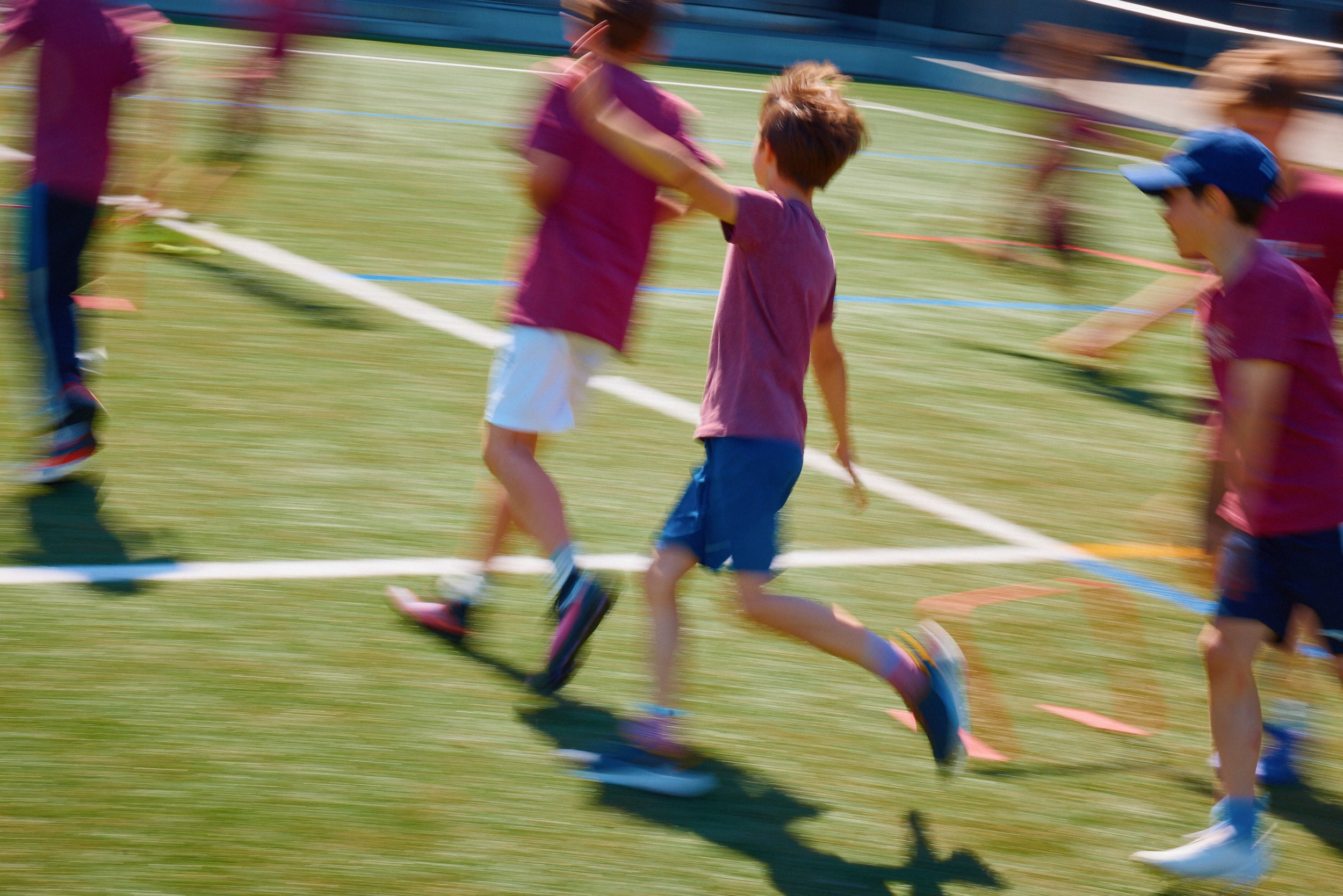 Kinder spielen und rennen auf einem Sportplatz.