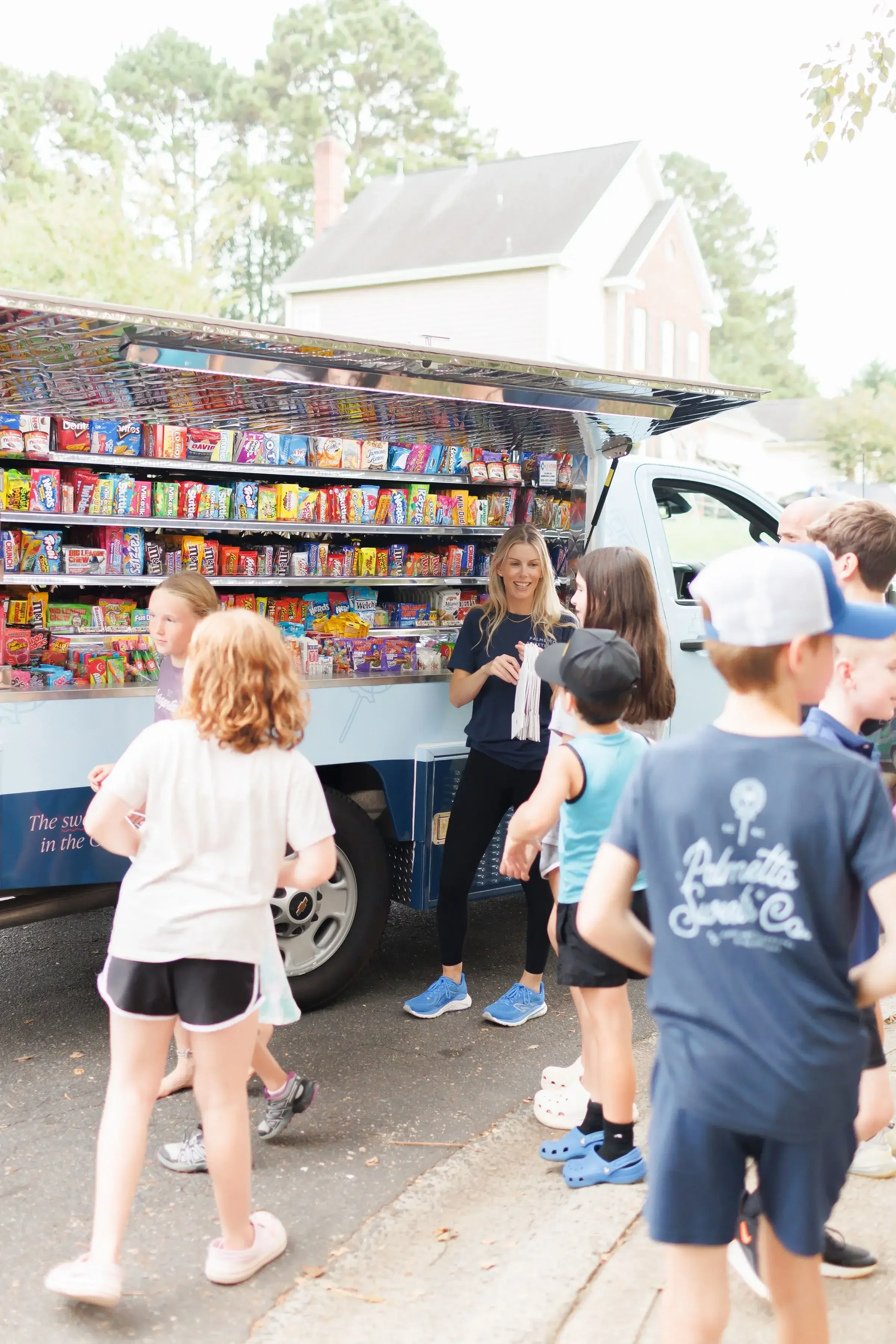 Palmetto Sweets Co. owner serving excited children from mobile candy truck at Charlotte area community event