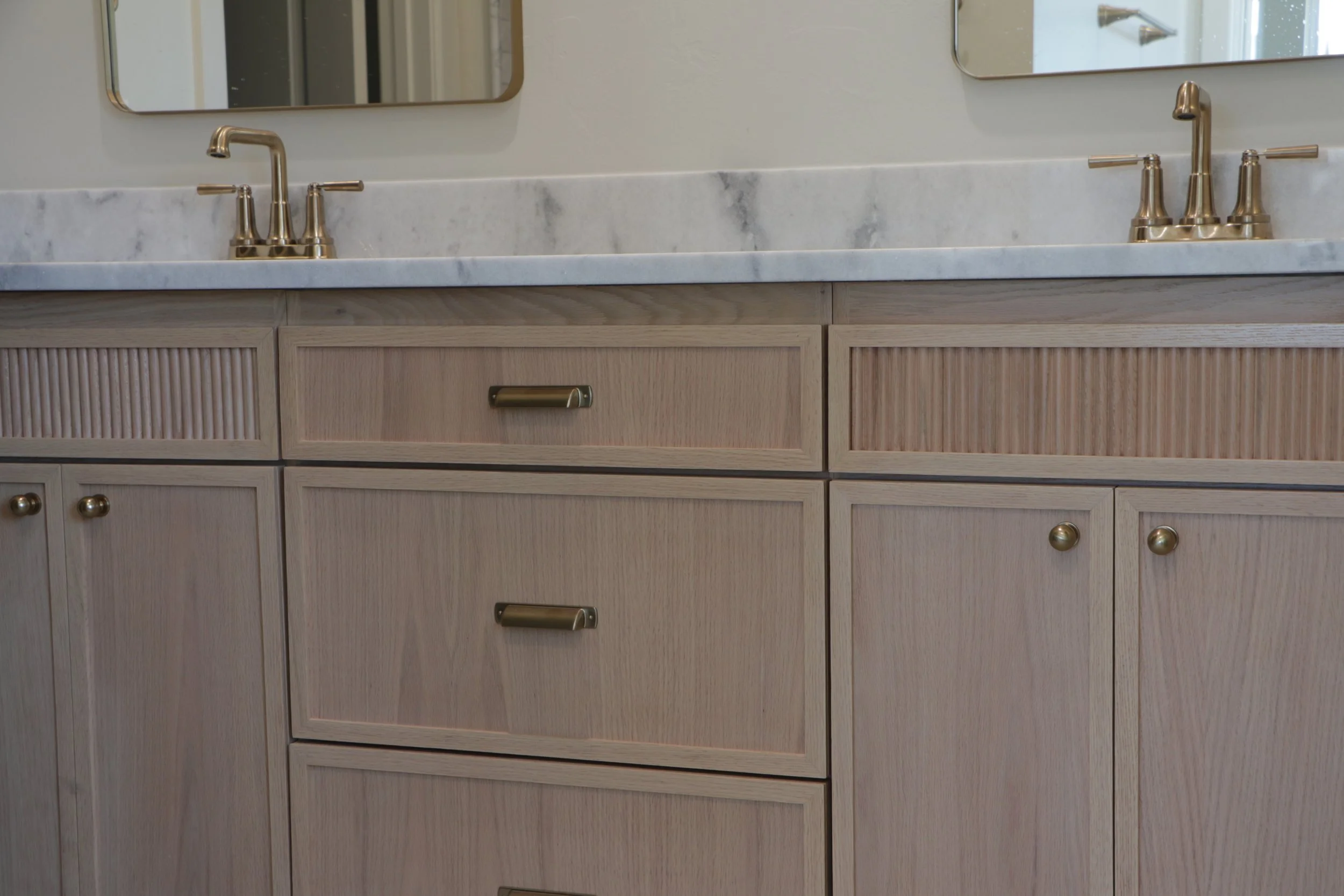 Custom bathroom cabinet featuring rift-sawn white oak shaker doors and reeded drawer fronts in OKC.
