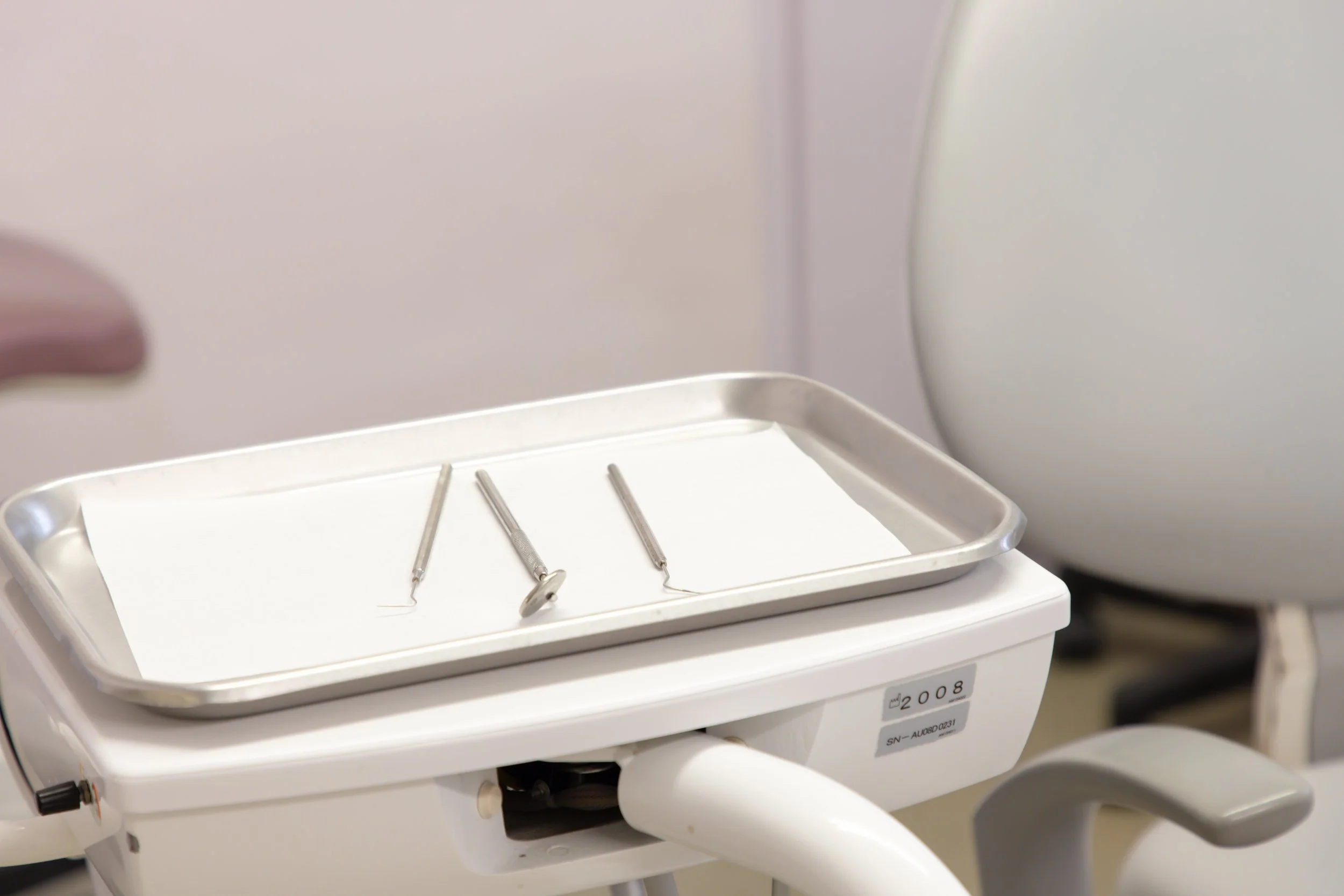 Dental instruments on a tray placed on a dental chair bench in a dental clinic.