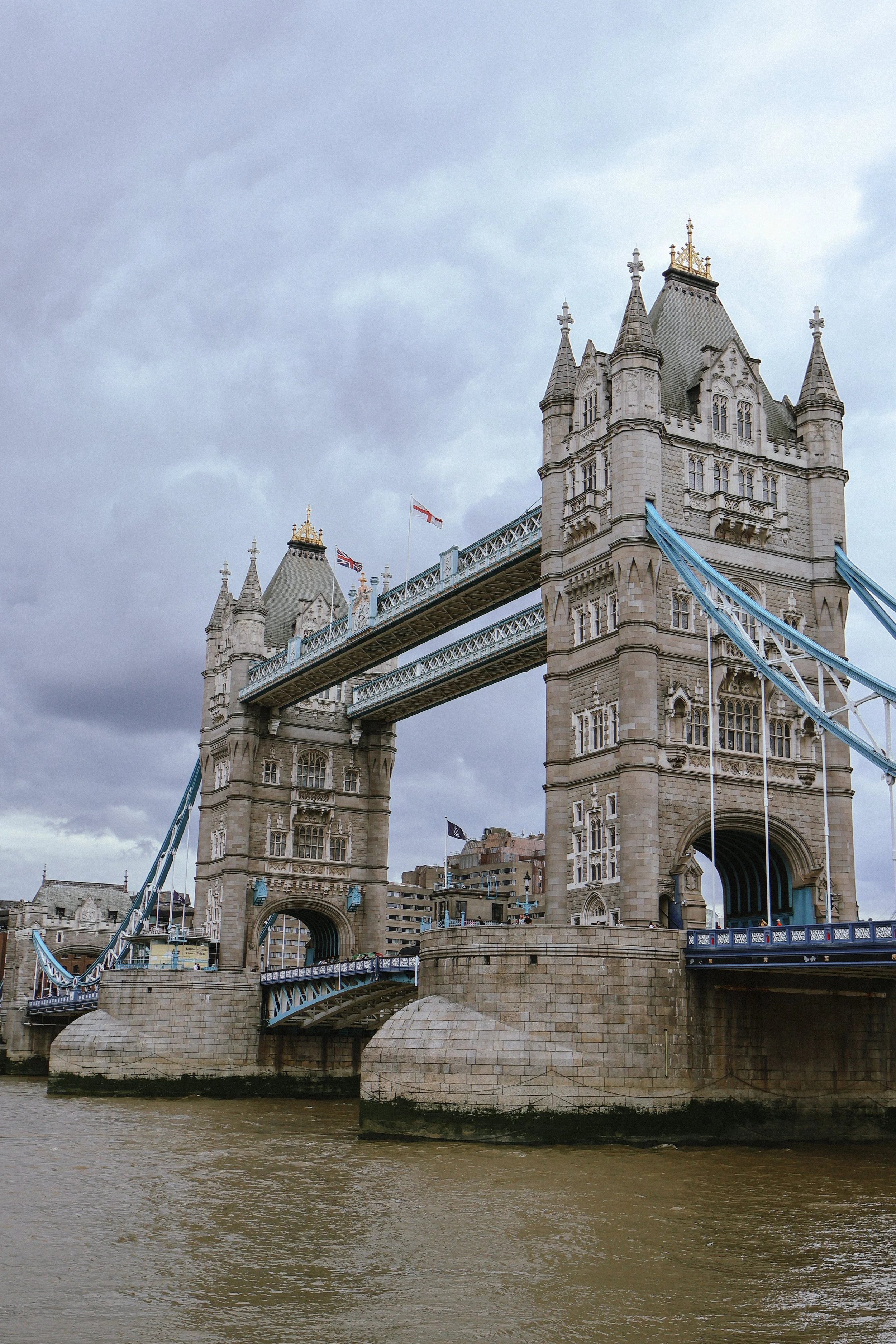 London's Tower Bridge with cloudy sky and River Thames in the foreground.