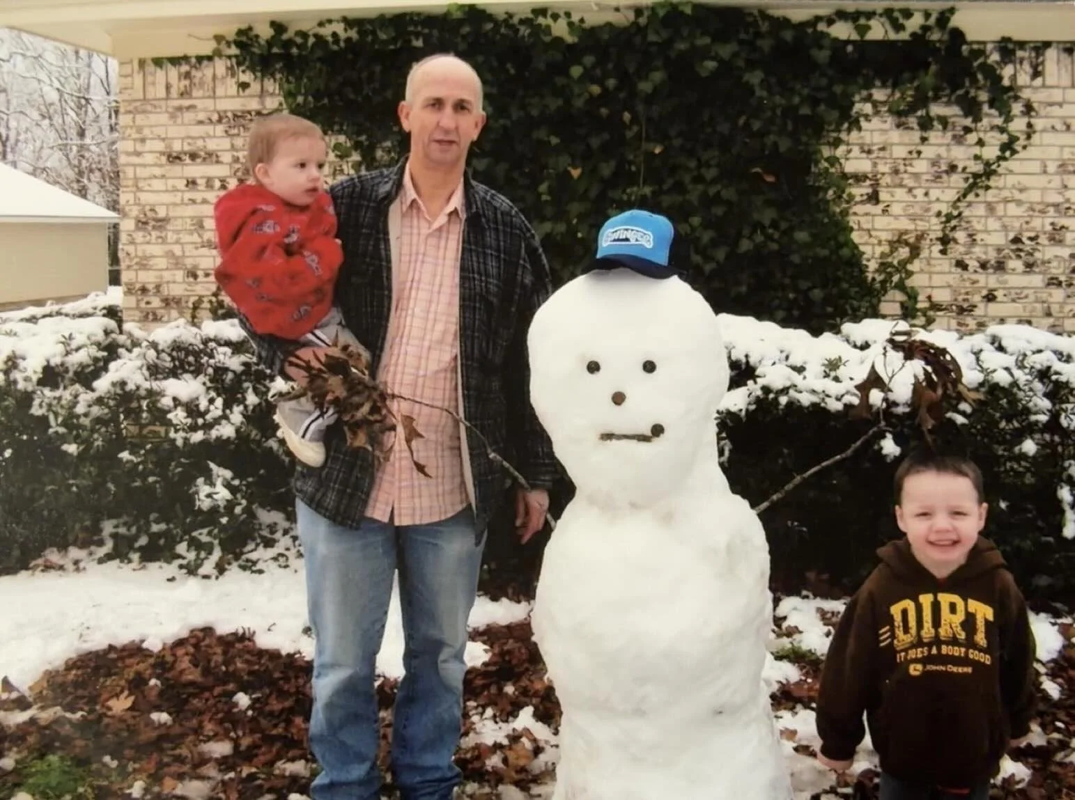 A young Kyler Allen with his grandfather and brother building a snowman in East Texas