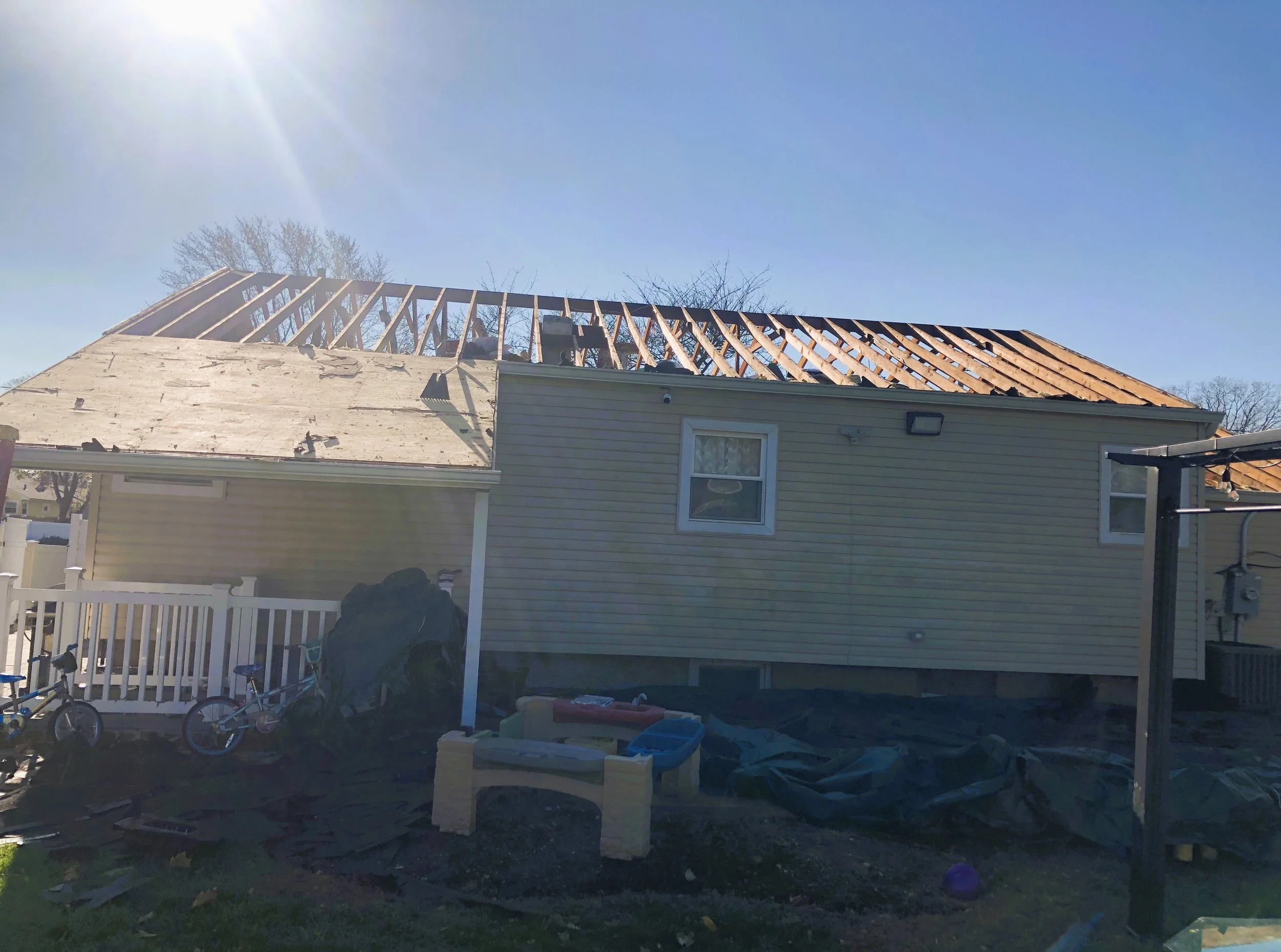 Back of a house with construction in progress, partly built roof with wooden framing.