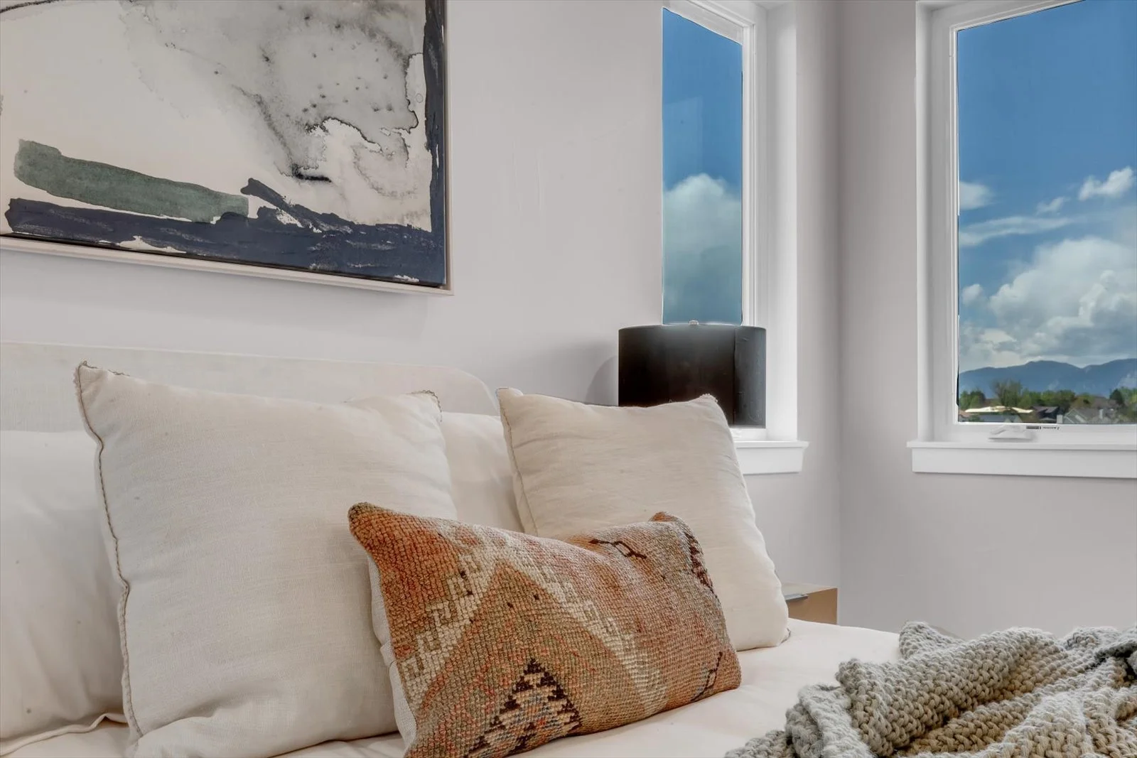 Bedroom detail with cream pillows, a patterned cushion, and a mountain view