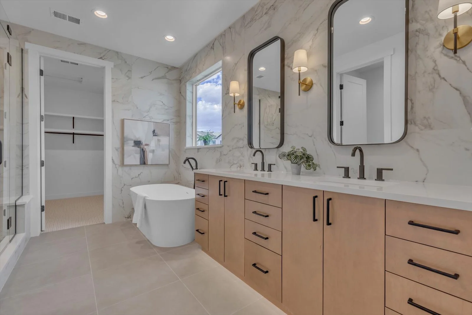 Bathroom with a wood double vanity, arched mirrors, and a freestanding tub